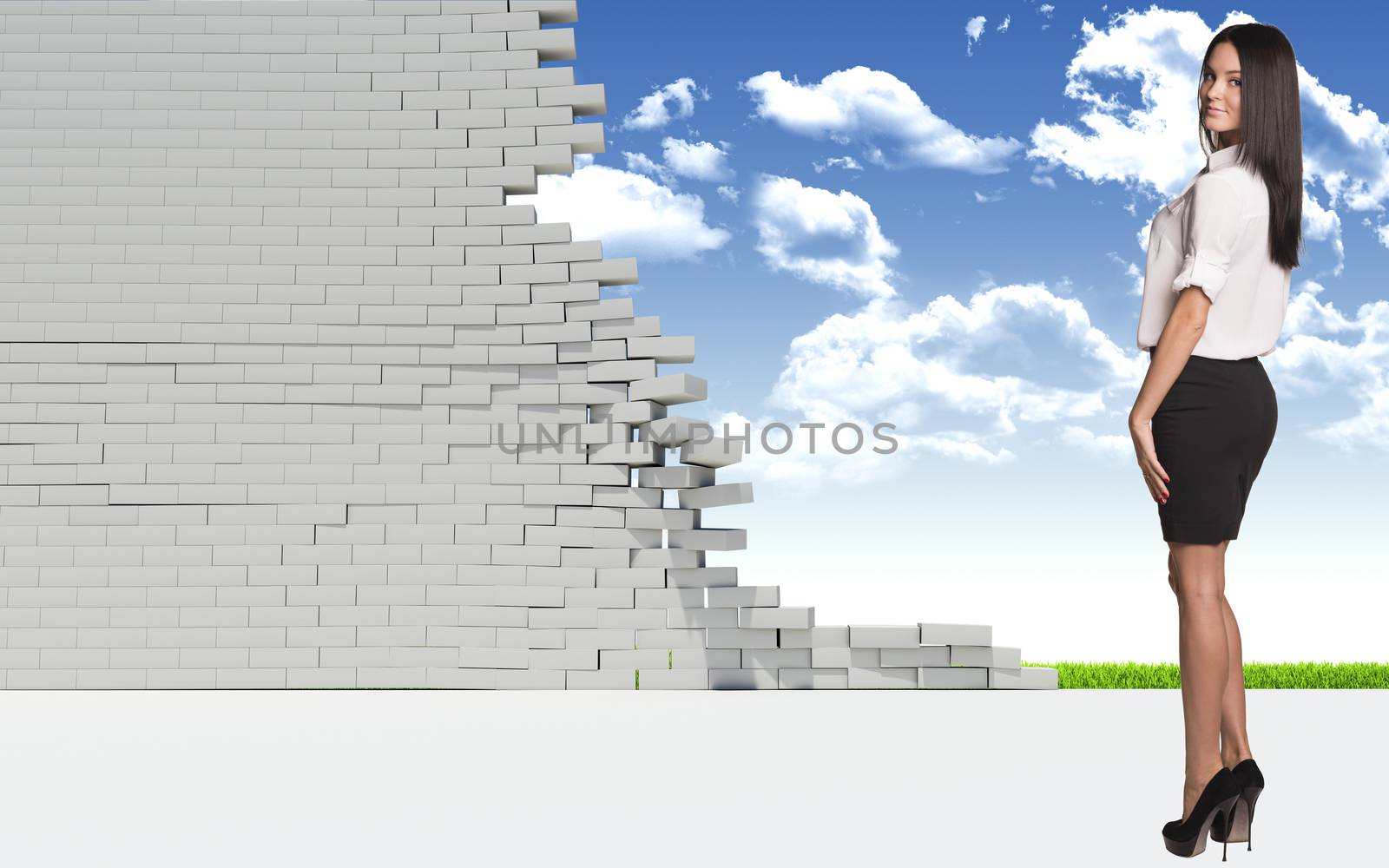 Beautiful businesswoman in shirt and skirt looking at camera. Dilapidated brick wall, green meadow with sky as backdrop by cherezoff