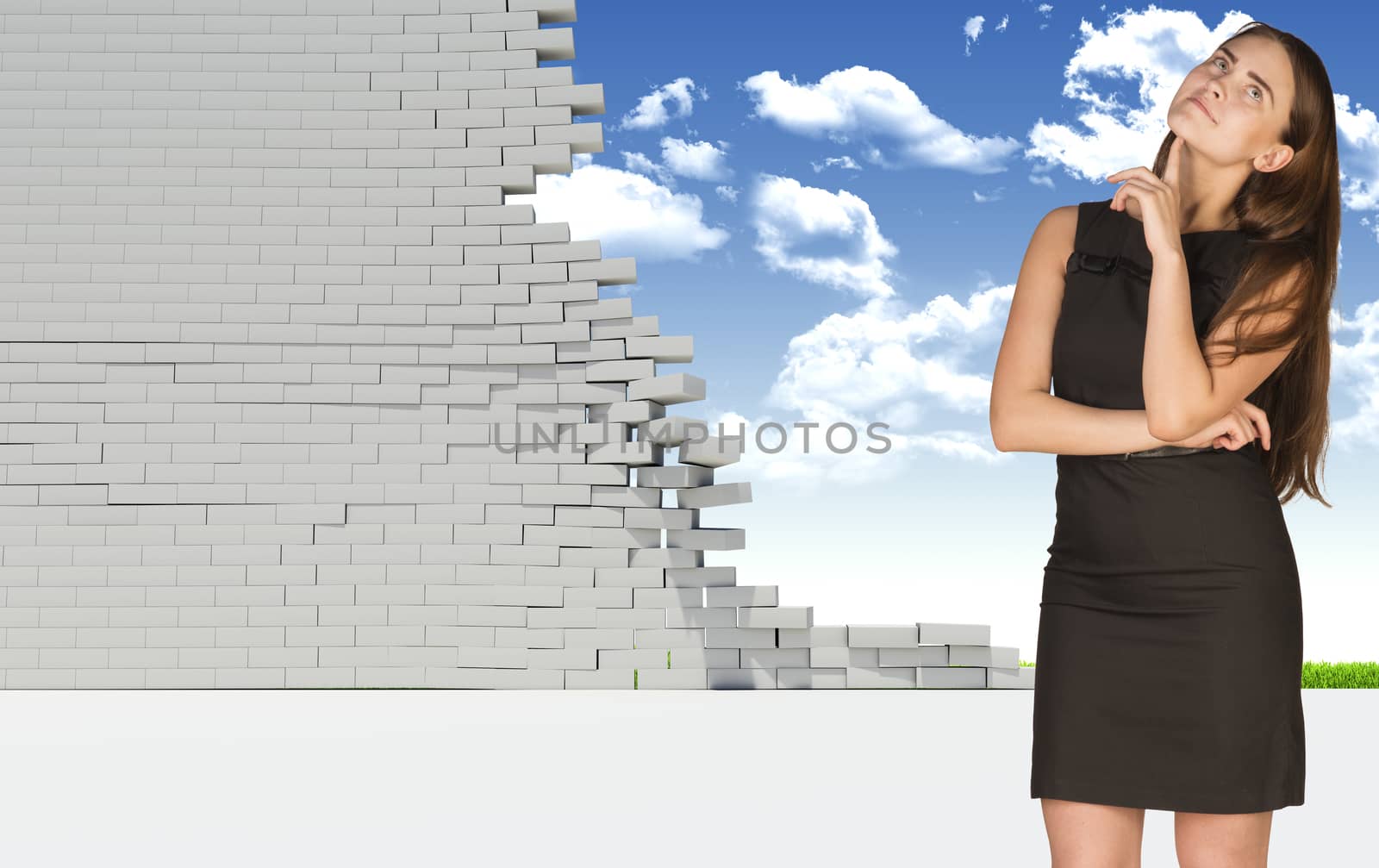 Thoughtful businesswoman in dress with crossed arms looking up. Dilapidated brick wall, green meadow and sky as backdrop. Concept of freedom