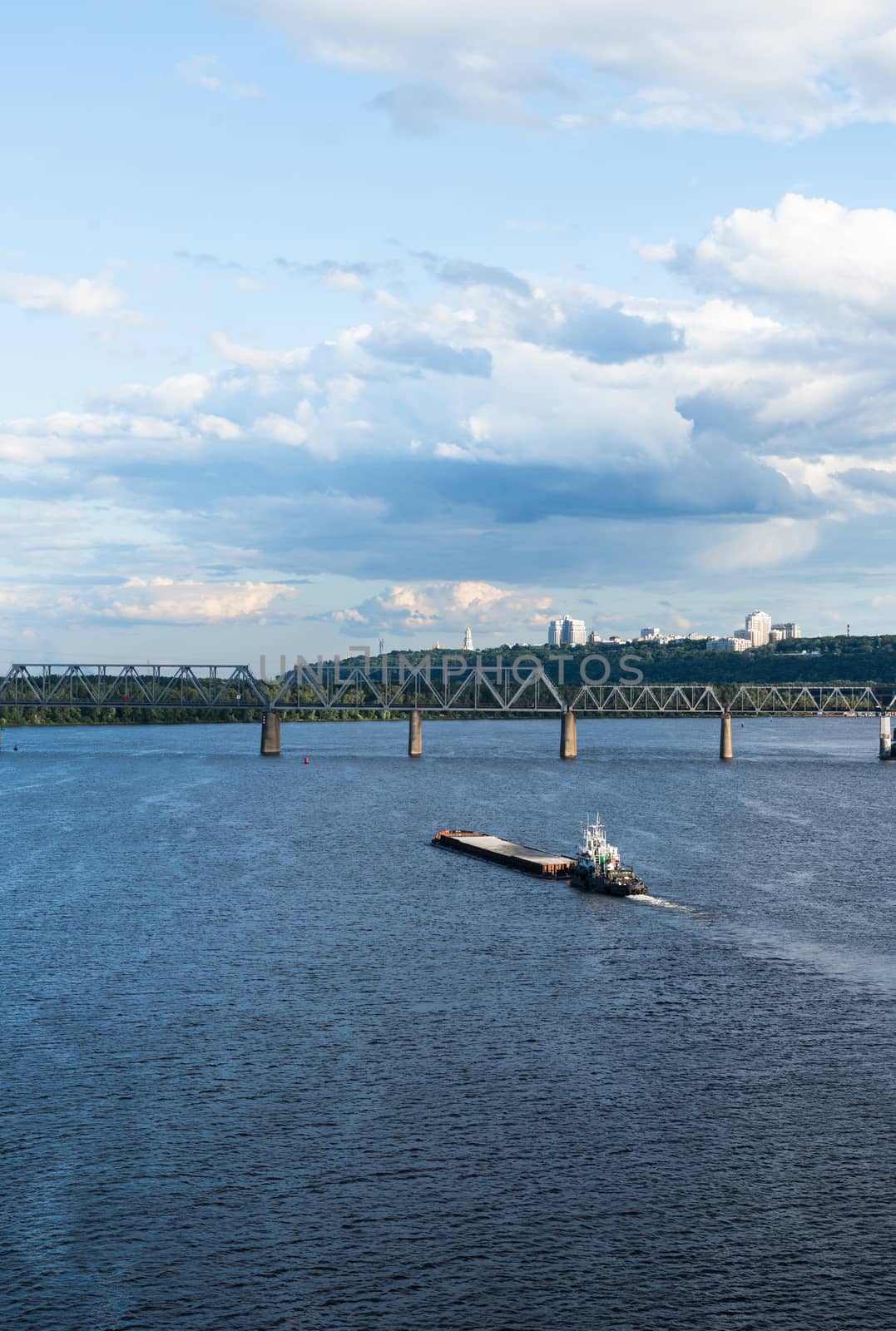 The barge floating in the blue Dnieper waters against the summer Kyiv landscape.