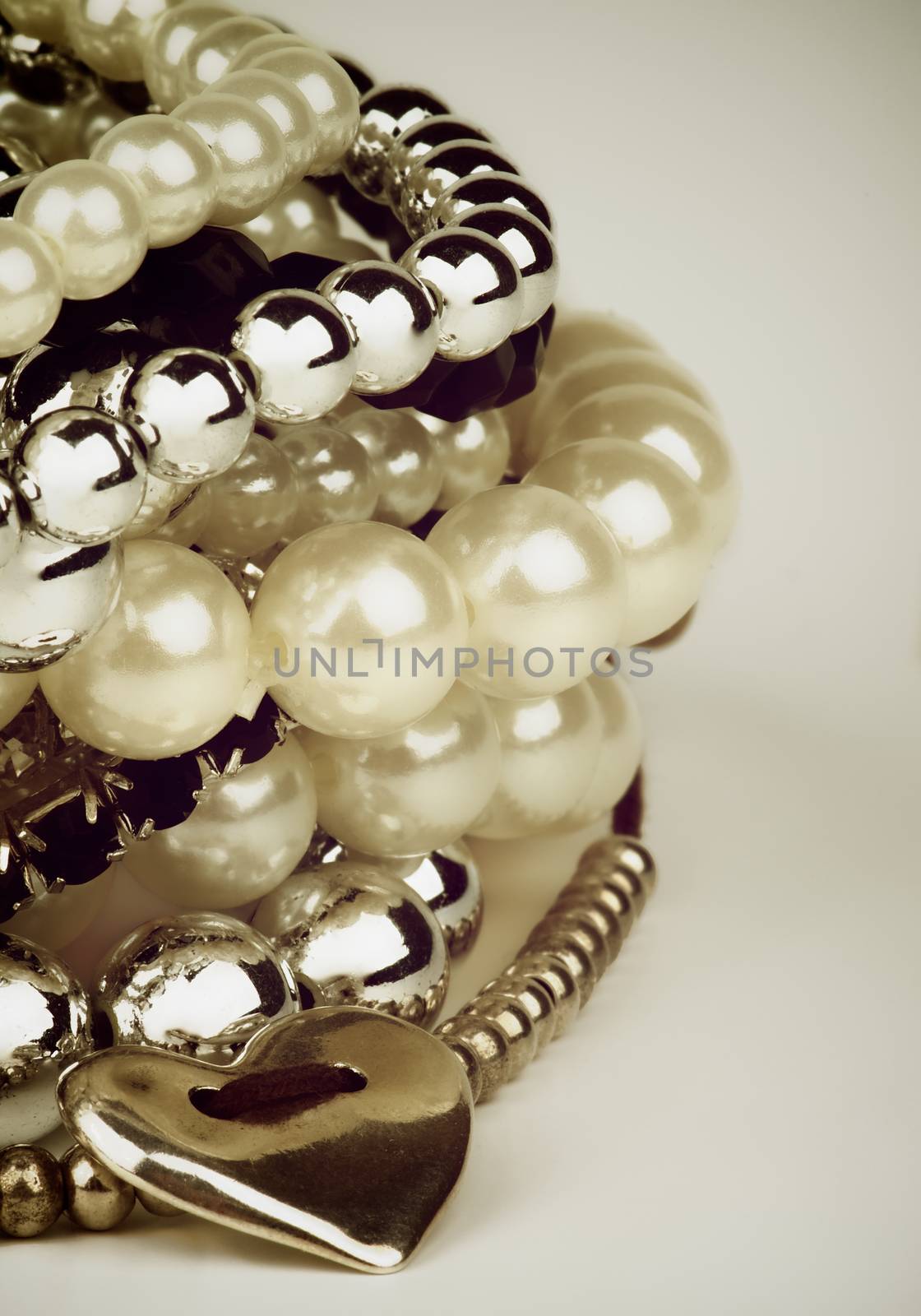 Stack of Various Pearl, Silver and Black Jewelry Gems Bracelets with Silver Heart Shape closeup. Retro Styled