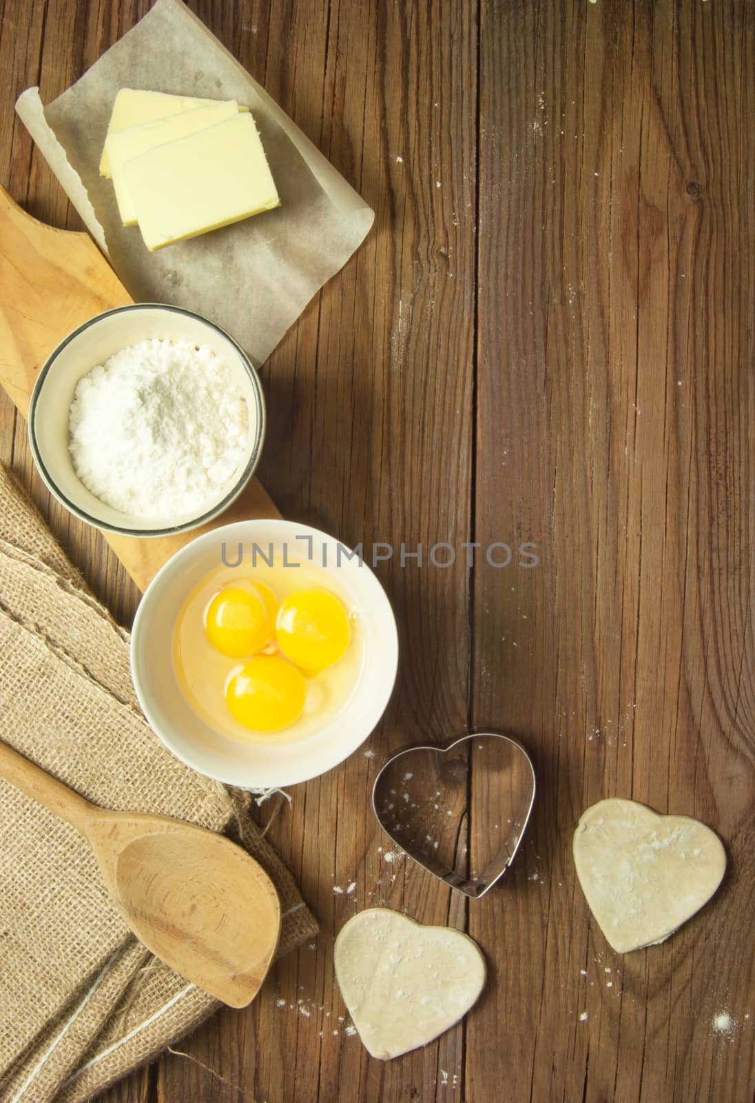Baking preparation ingredients including eggs, flour and heart shape cookie shapers