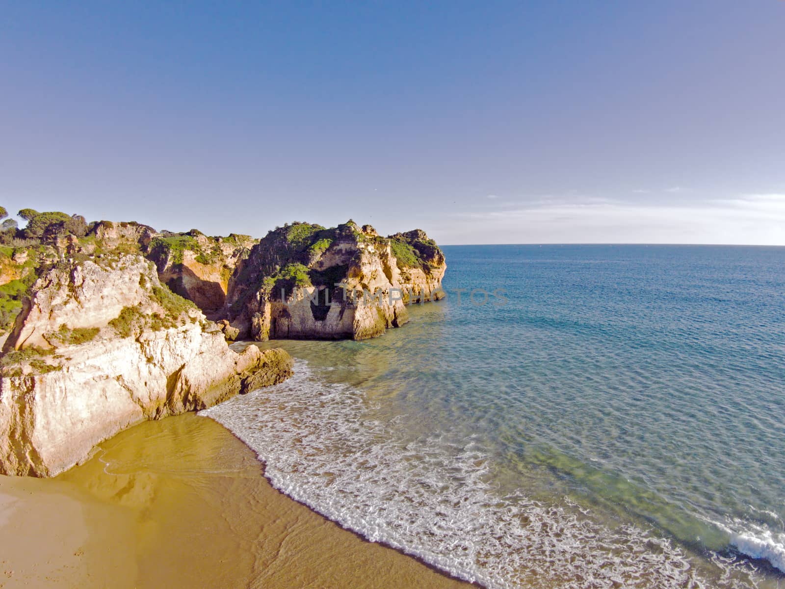 Aerial from rocks and ocean at Praia tres Irmaos in Algarve Portugal