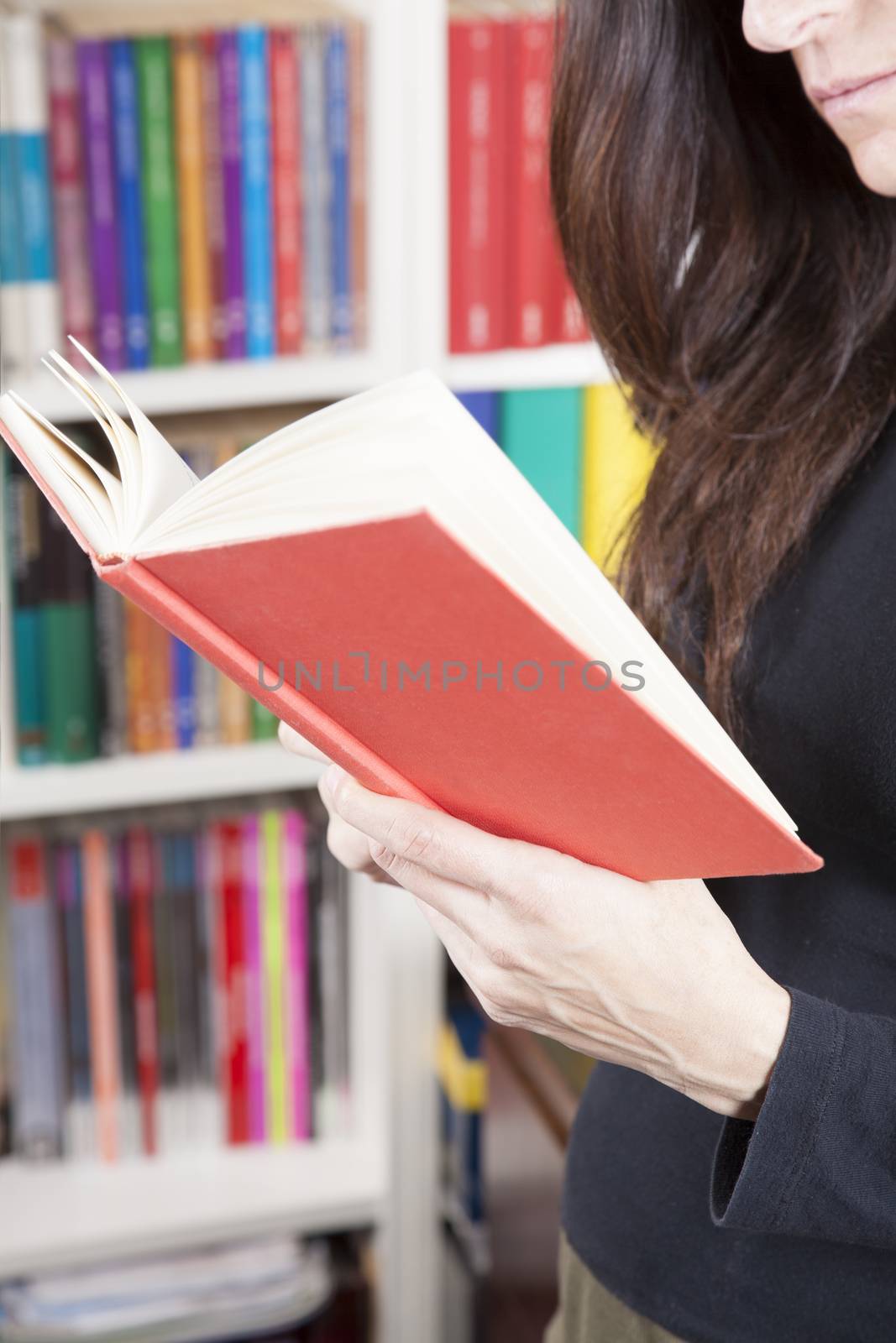 red book in black shirt brunette woman hand over library background