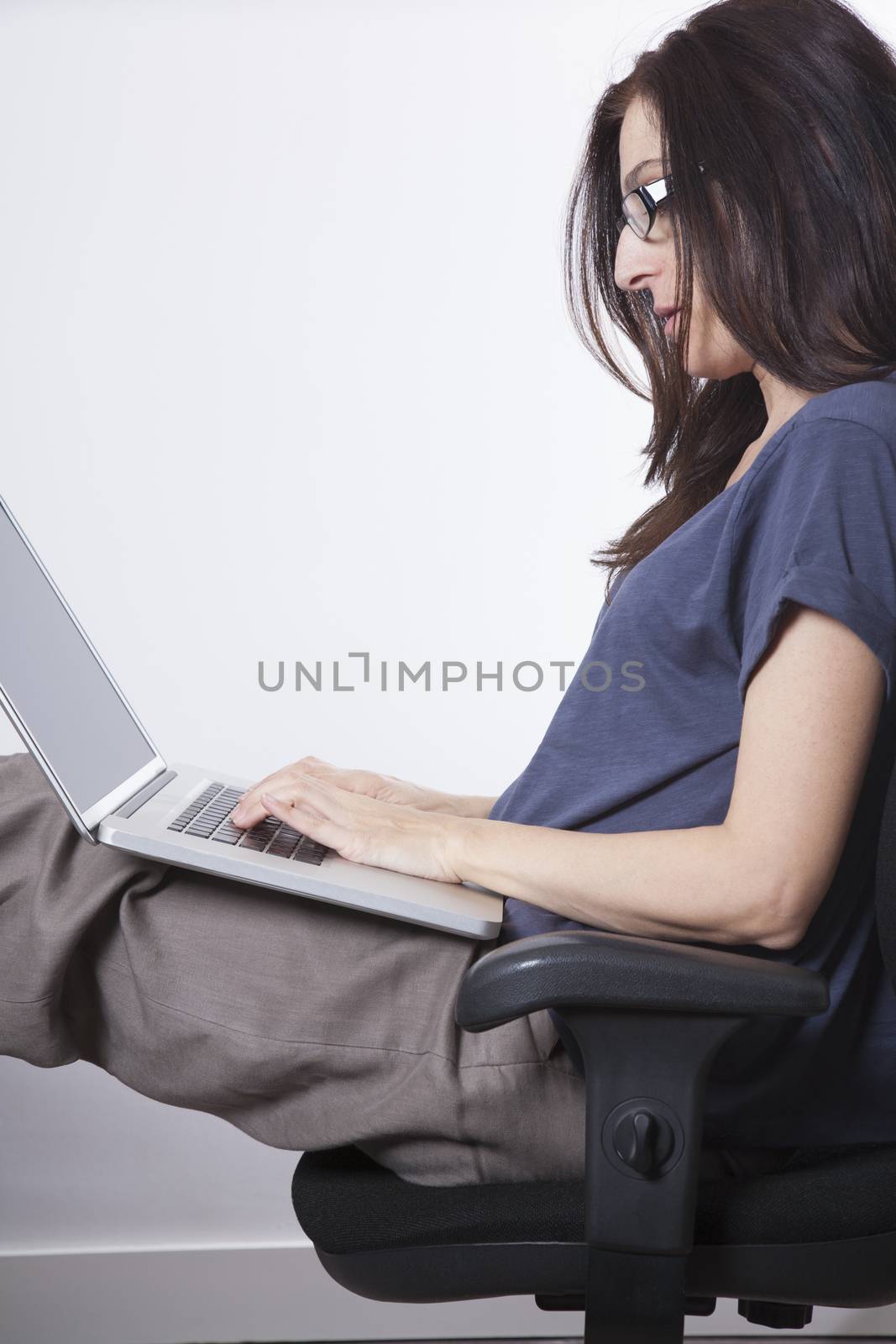 woman blue shirt sitting at black seat in office typing on laptop
