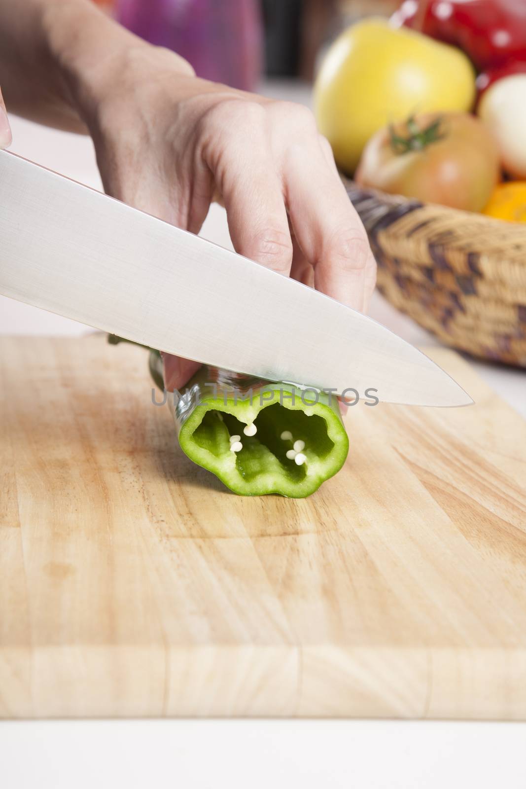 woman hands cutting green fresh pepper slices on brown wood plank white worktop