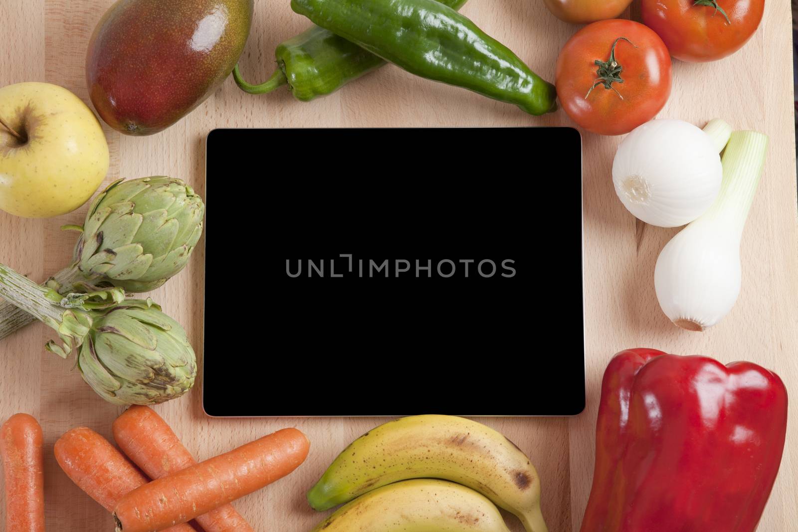 blank screen tablet still life fruits and vegetables around on brown wood plank