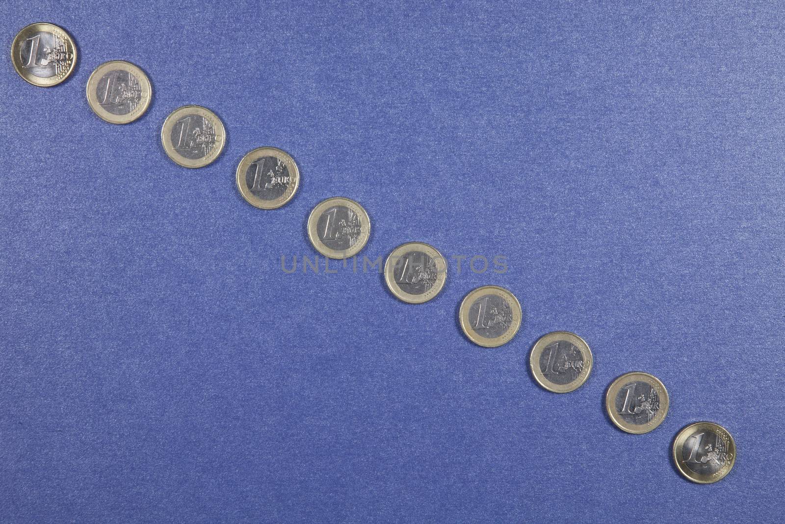 One Euro coins in a row from top to down on blue background