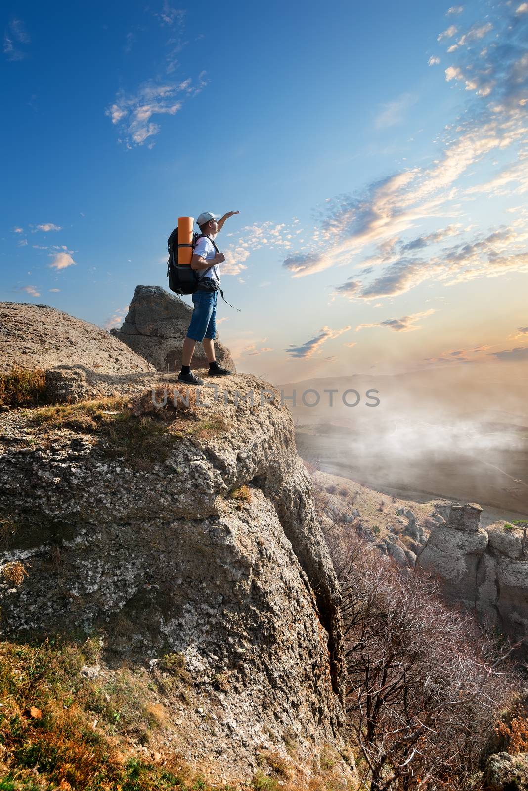 Tourist on a high rock at sunrise