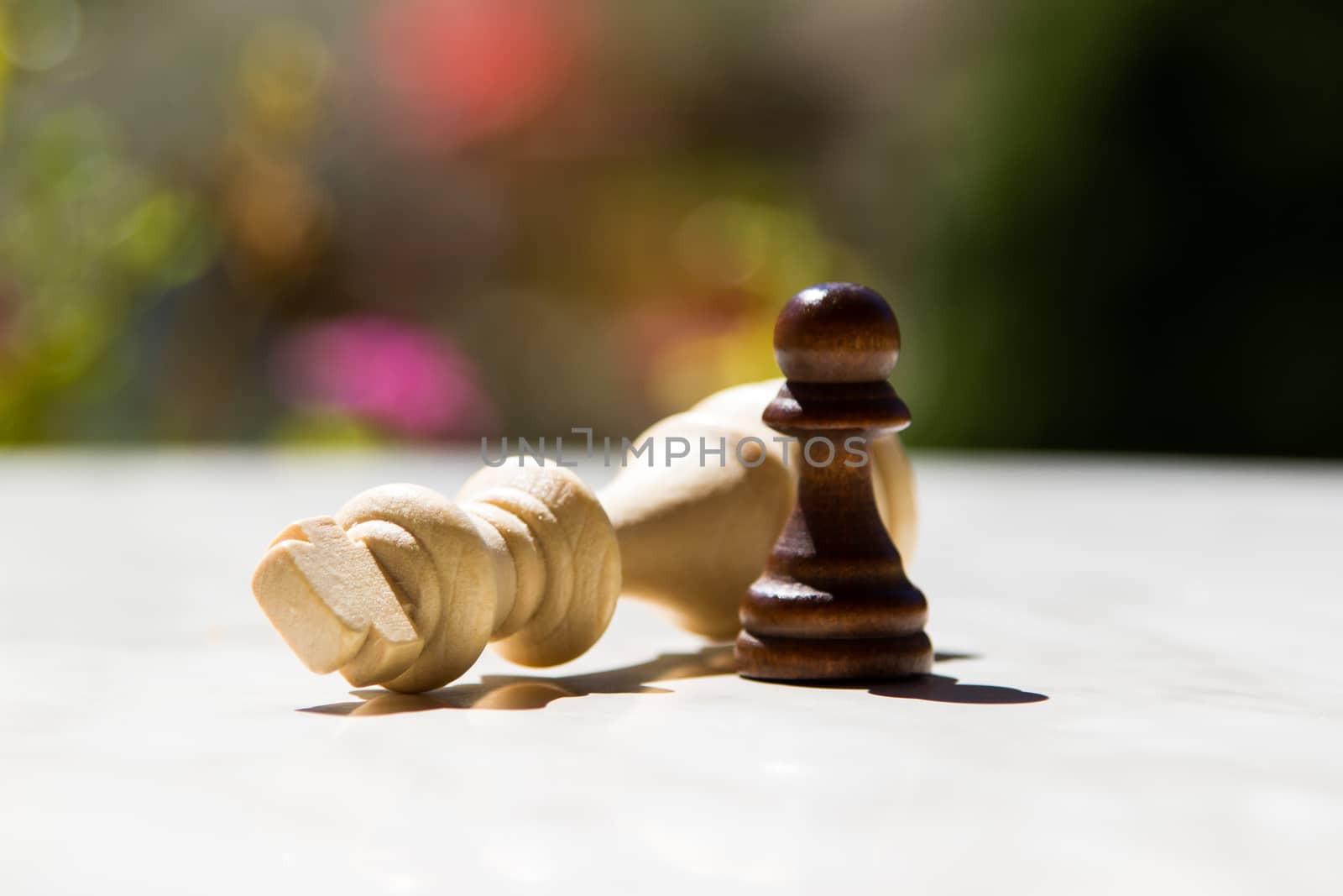 Chess pieces, pawn and queen on white table with blurry background.