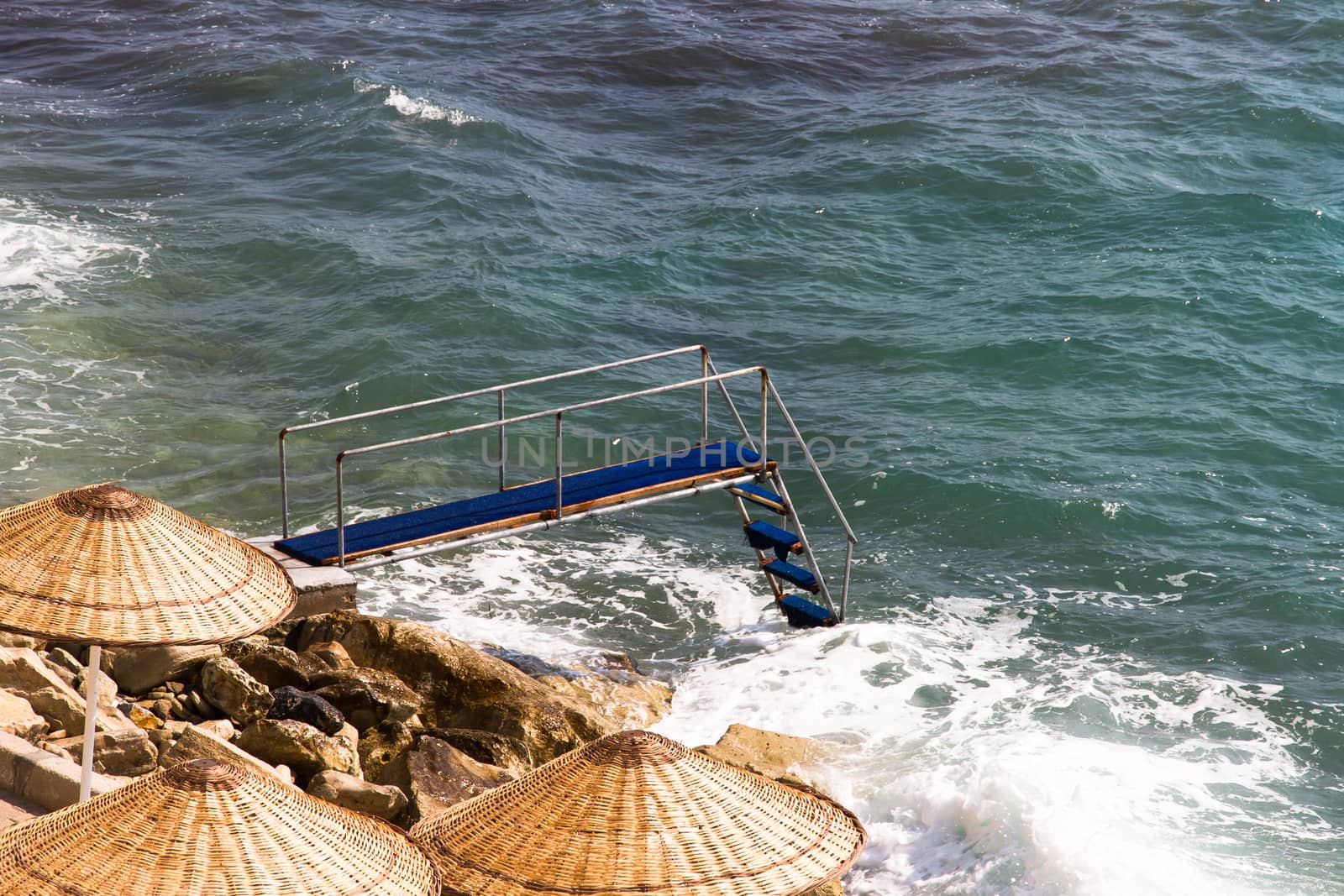 Pier on wavy clean sea.