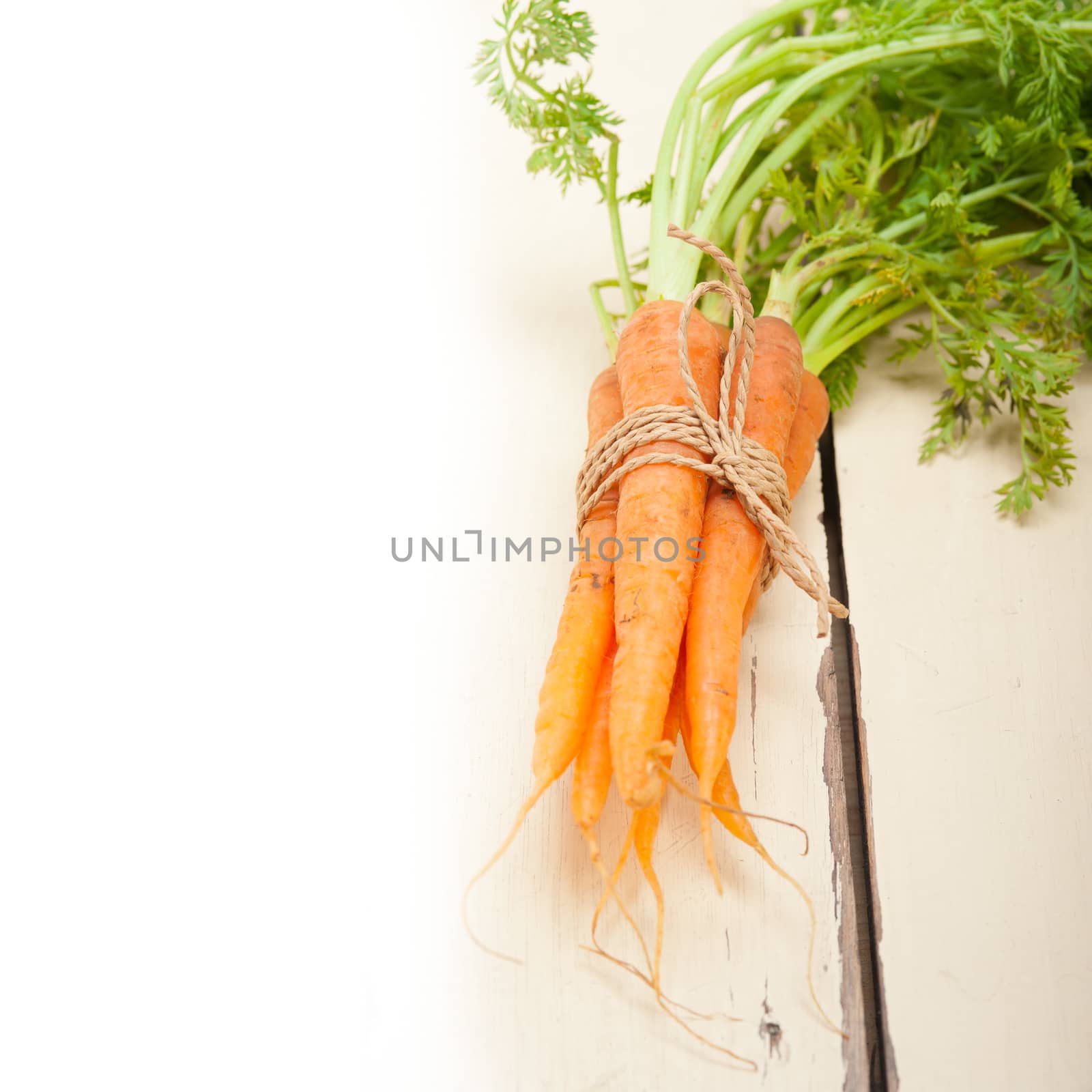 fresh baby carrots bunch tied with rope on a rustic table