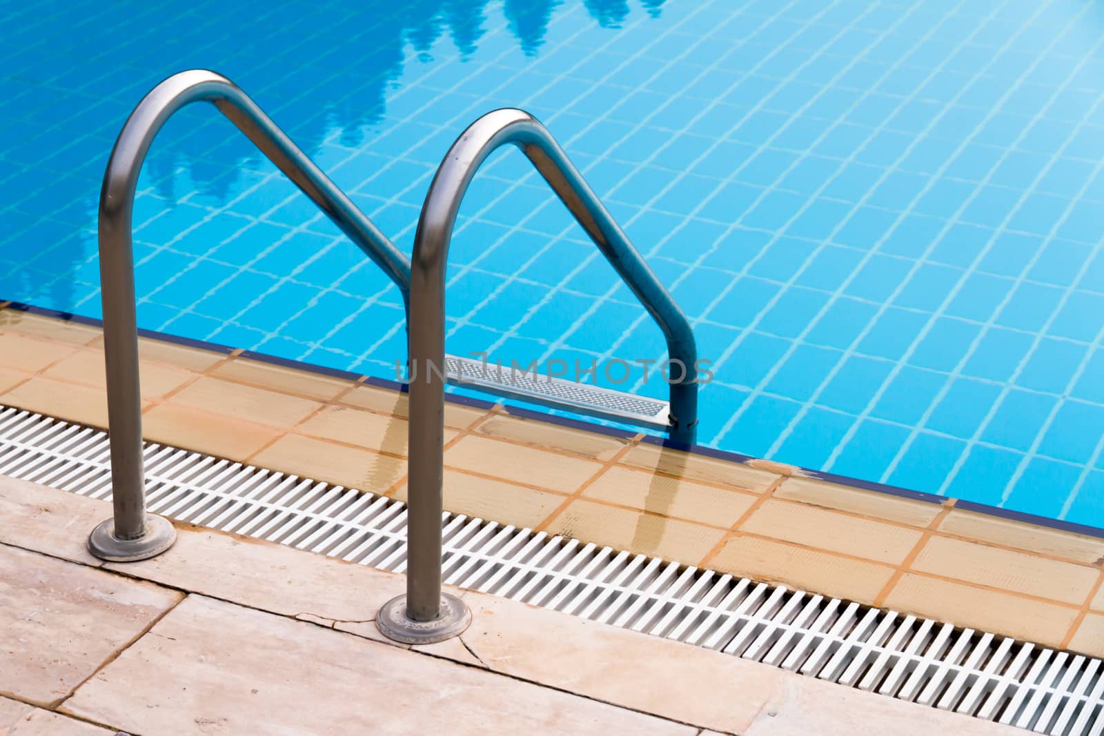 Blue swimming pool with stair at poolside.