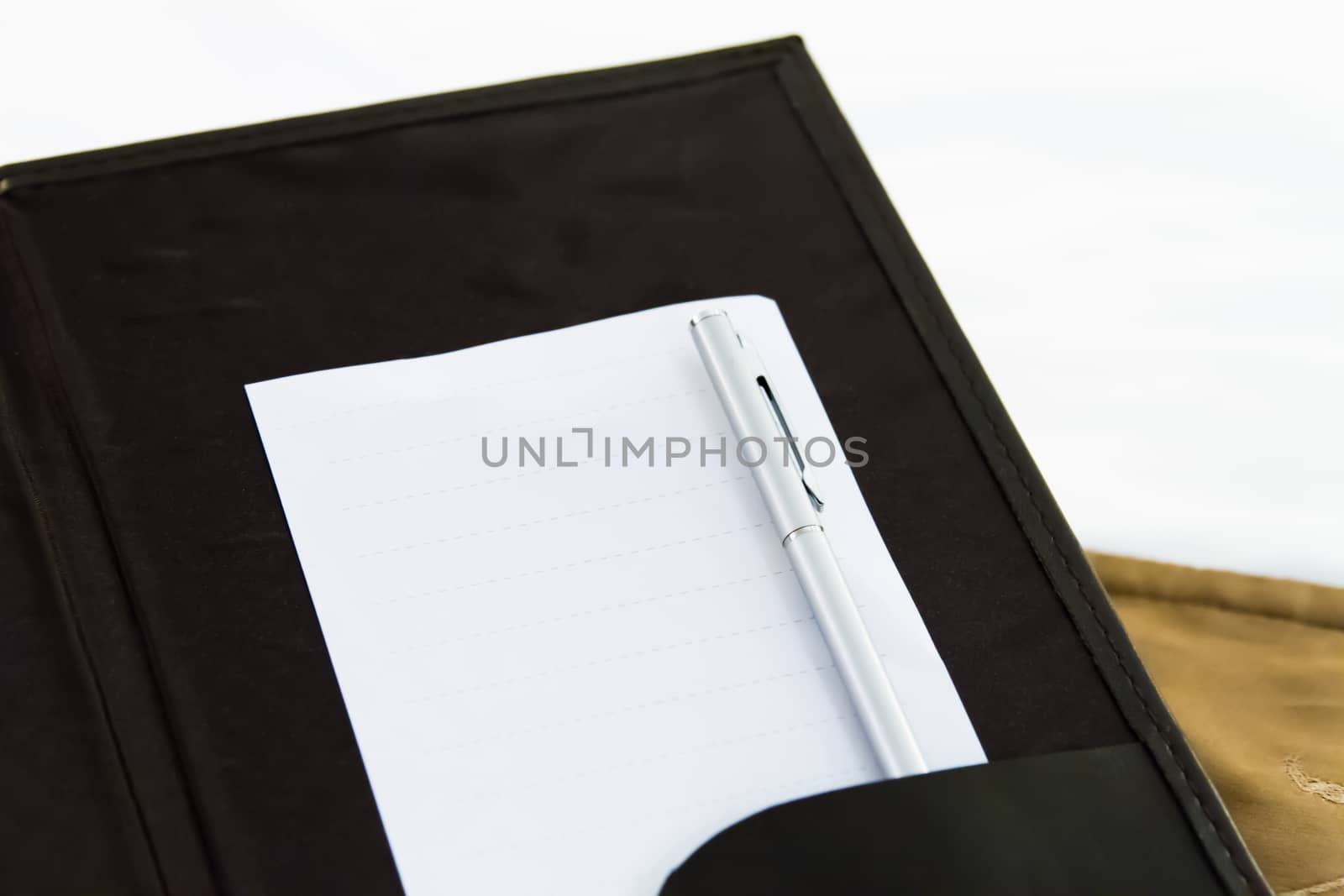 White blank note with pen on bed in hotel room.