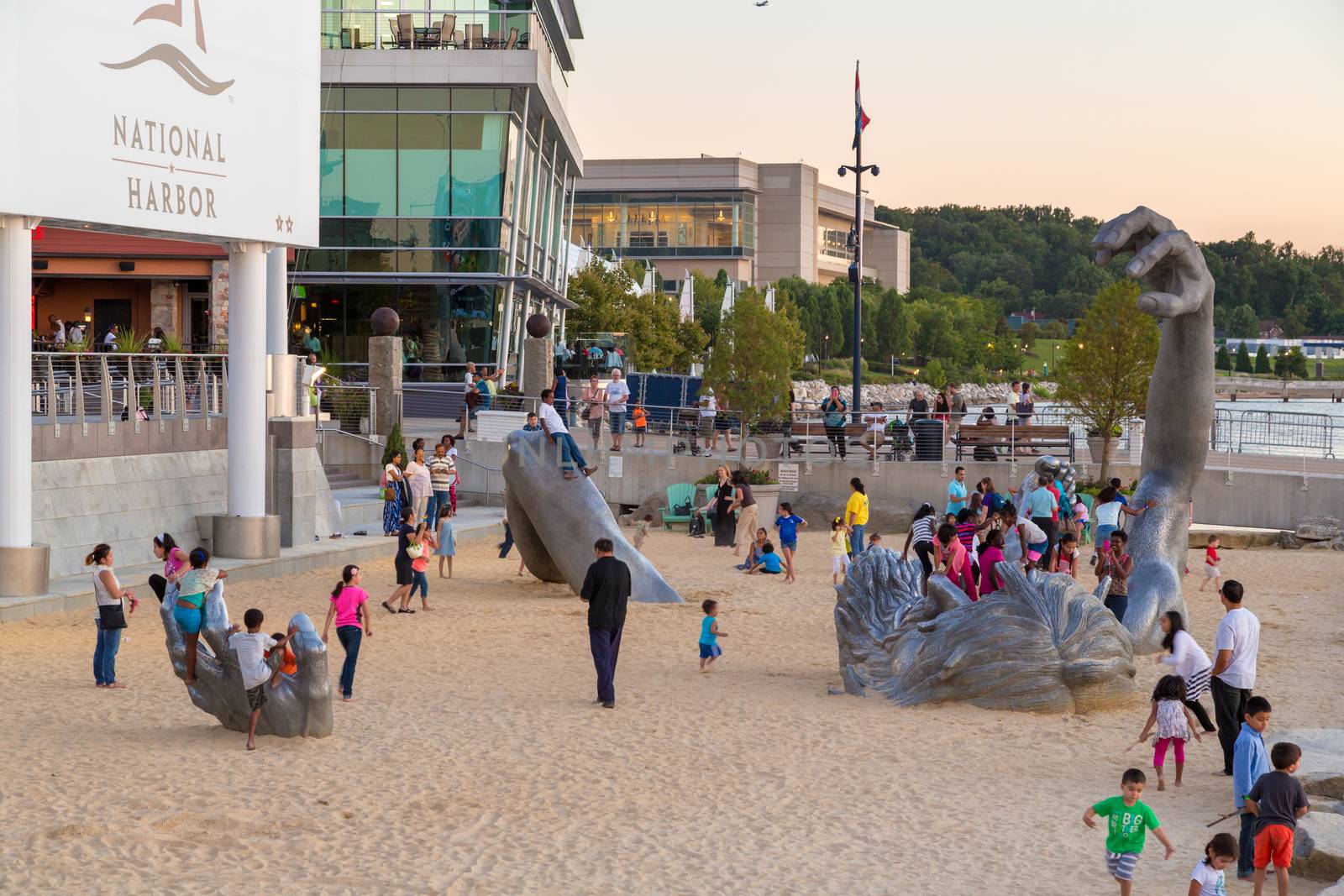 Children play on top of the awakening sculpture, a five piece aluminium figure of a giant man buried in the sand on Aug 28, 2014 at the National Harbor in Maryland, USA.