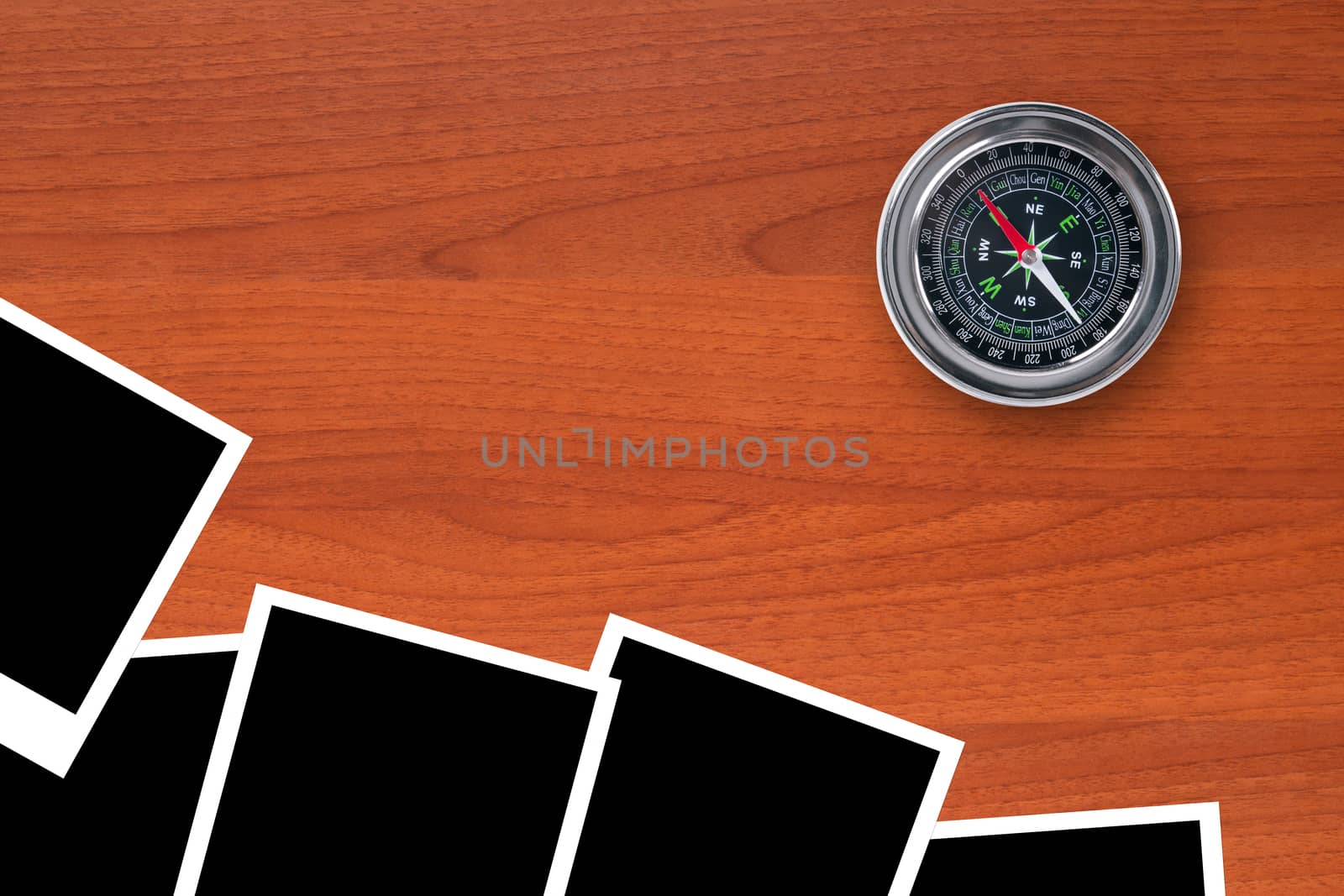 Blank, black picture frames with compass on wooden table.