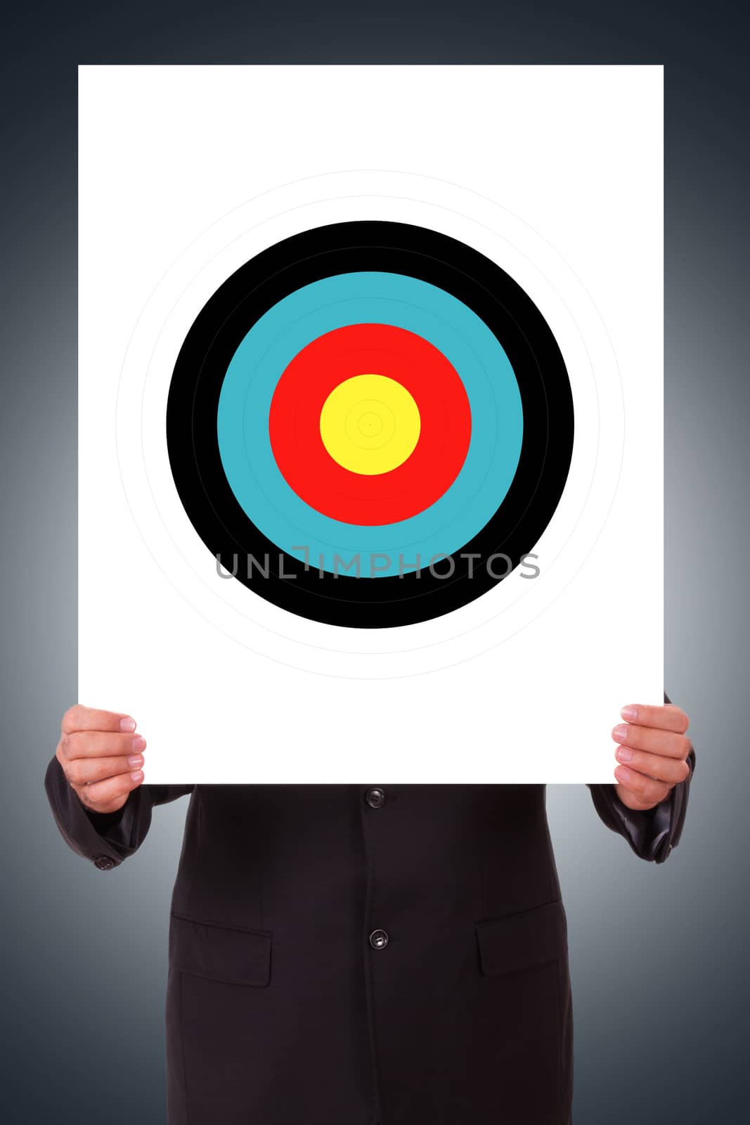Businessman hand holding white poster with colorful target on dark background.