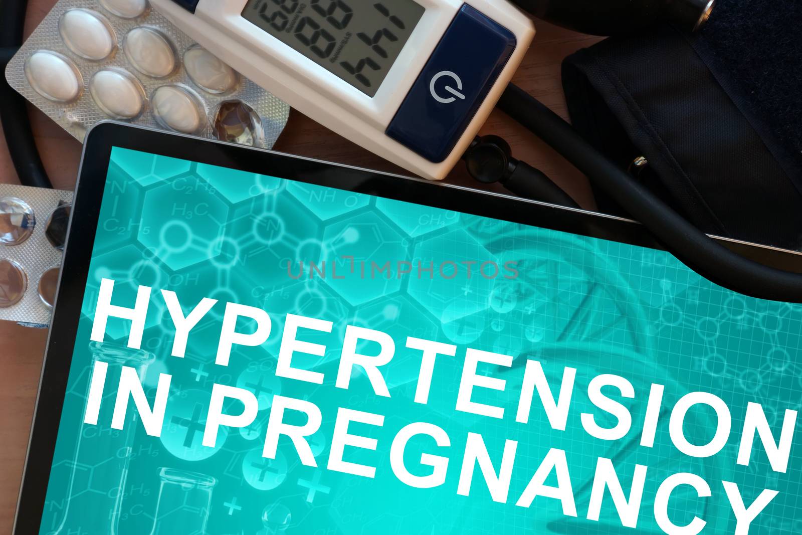 Tablet with the diagnosis Hypertension In Pregnancy and Electronic blood pressure monitor