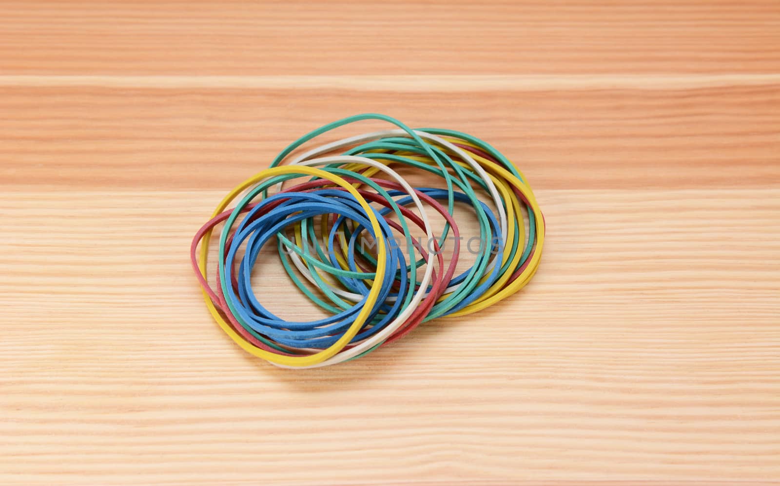 Small neat pile of coloured rubber bands on a wooden background