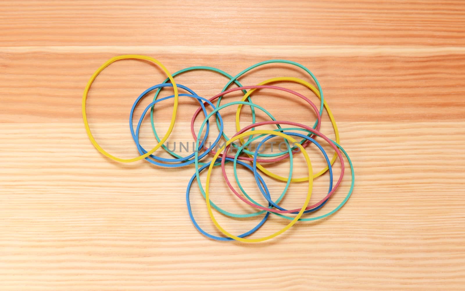 Handful of coloured elastic bands scattered on a wooden background