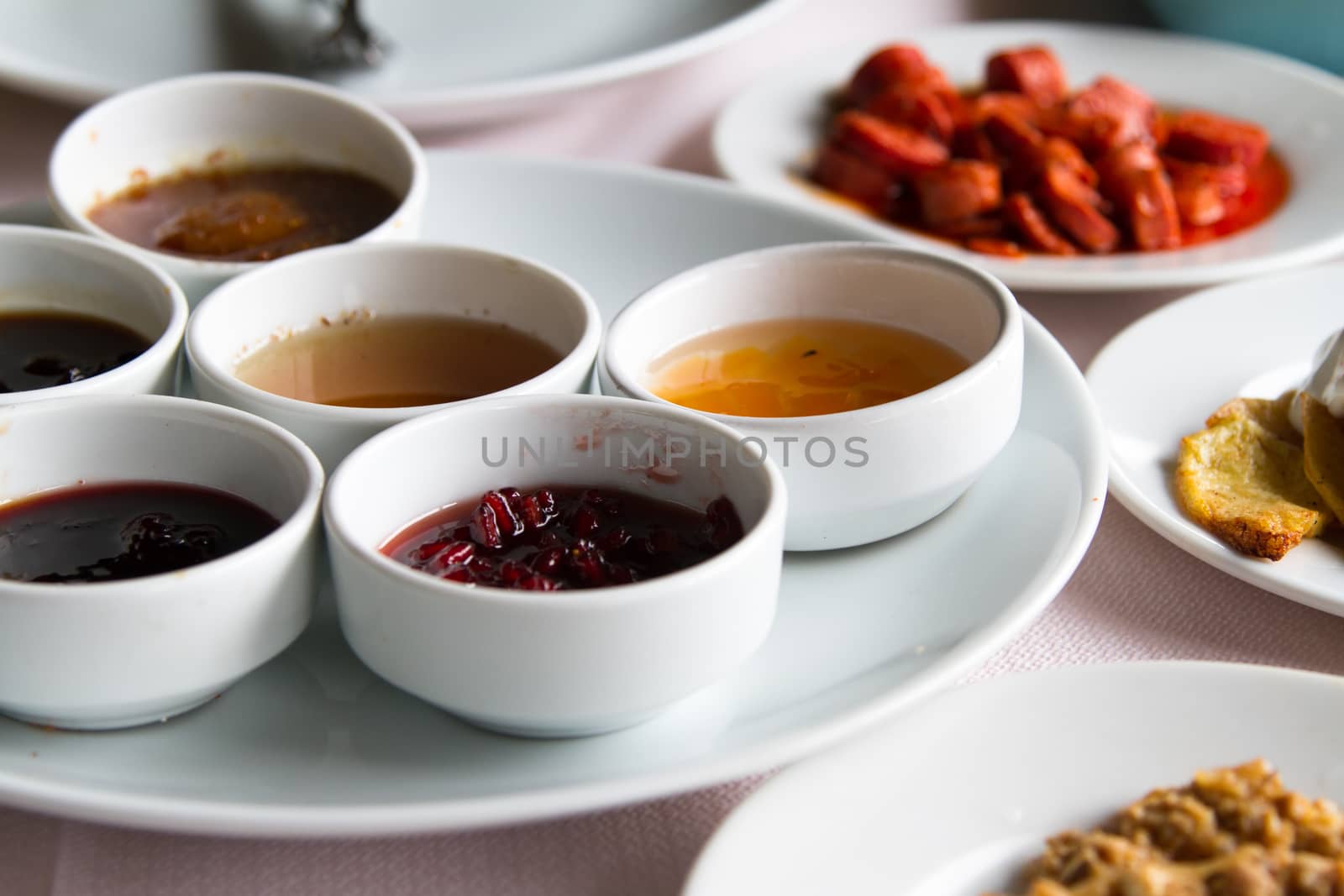 Breakfast service, jam and honey in white bowls on table.
