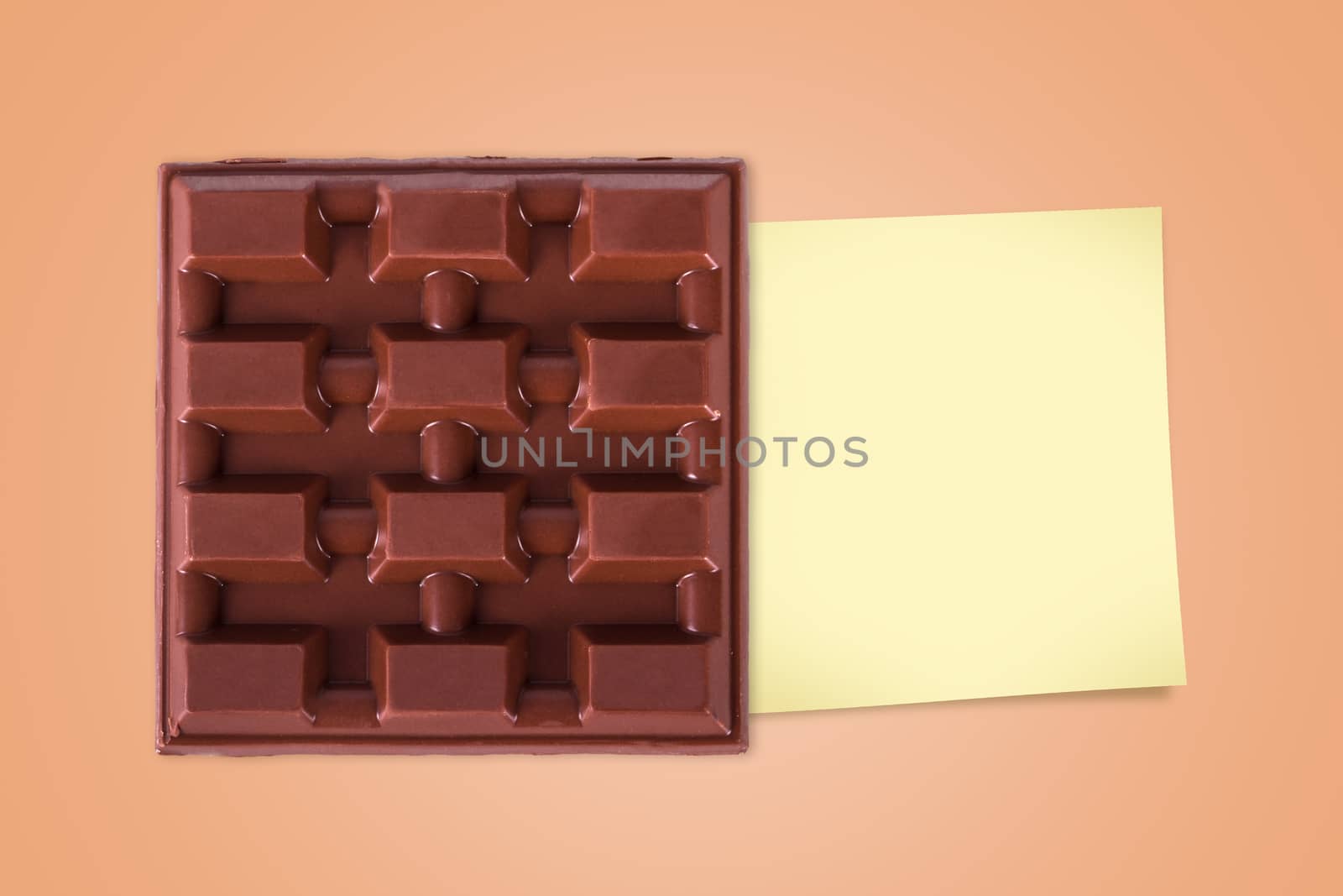 Top view of full milk bar chocolate with sticky post for your message on brown background.