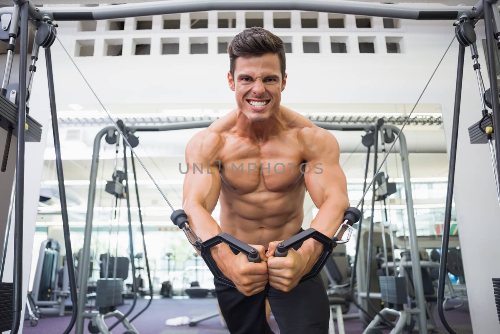 Shirtless muscular man using resistance band in gym by Wavebreakmedia