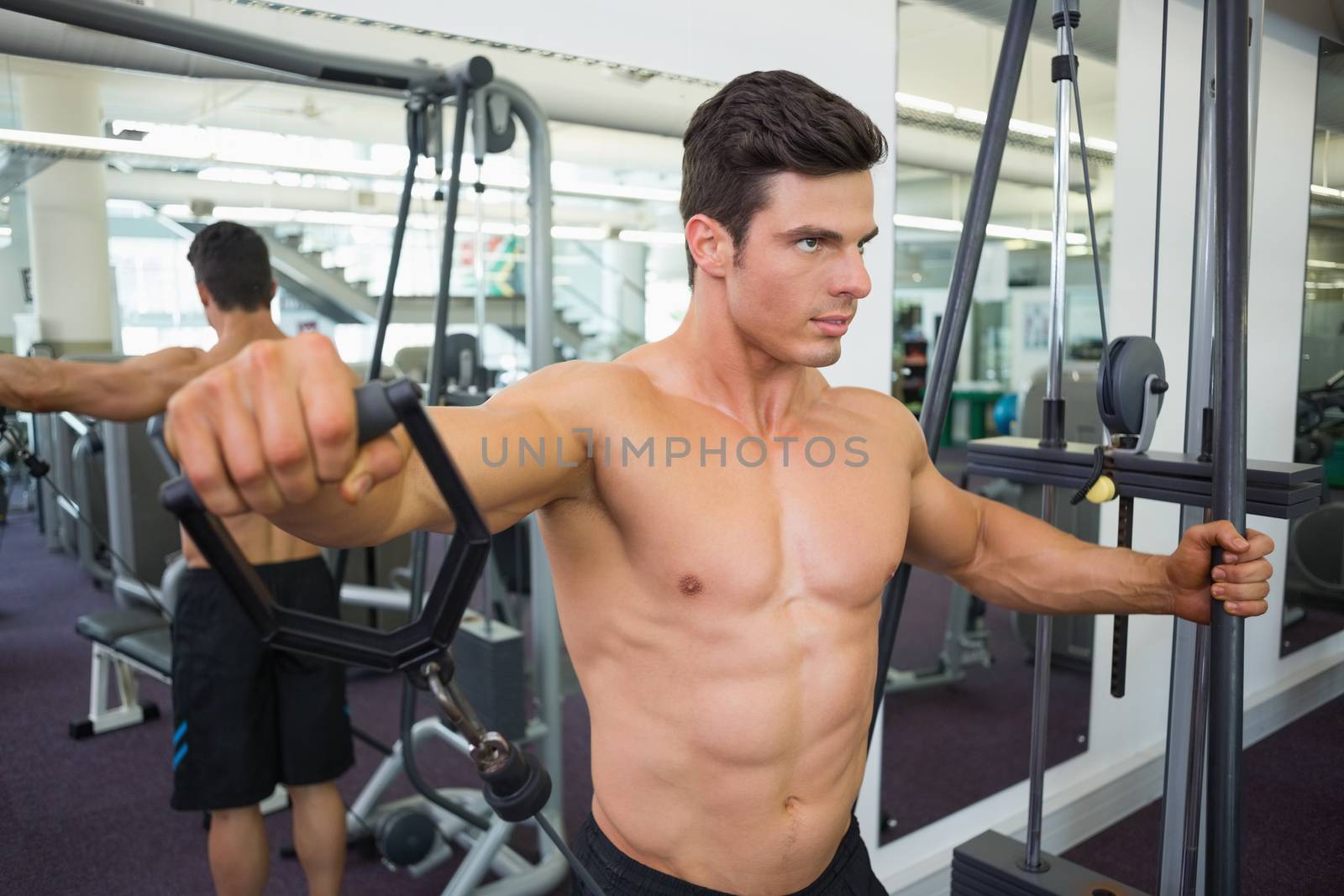 Shirtless muscular man using resistance band in gym by Wavebreakmedia