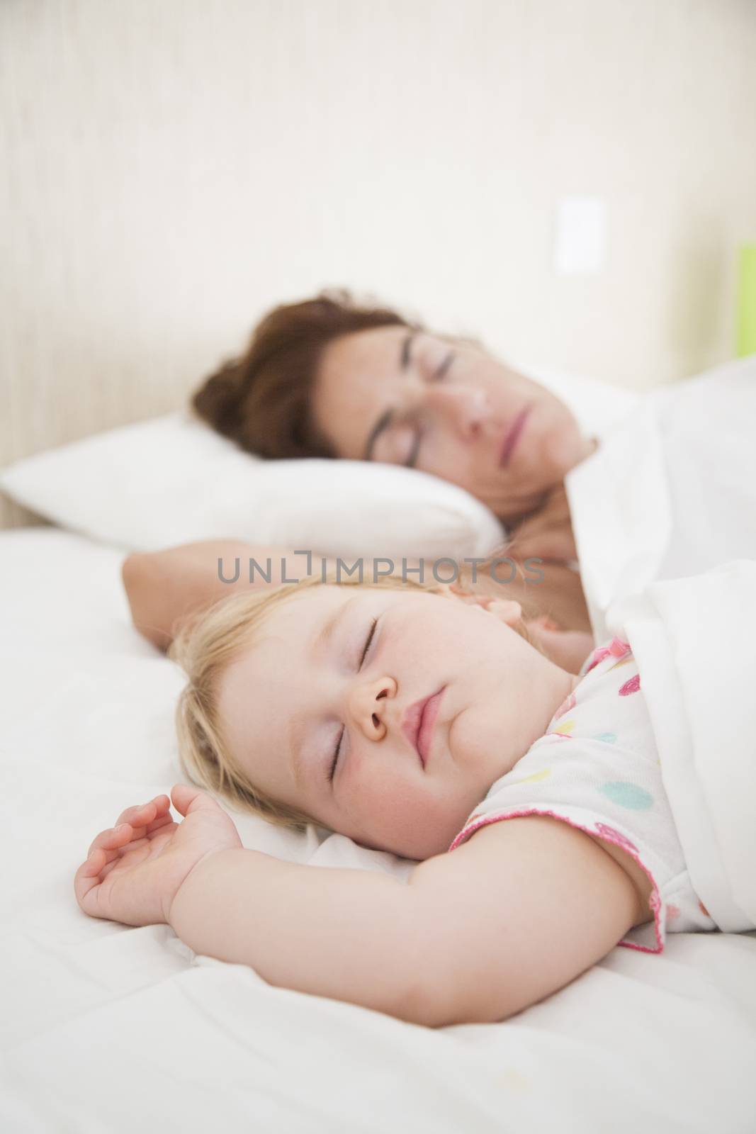 one year baby face and woman mother sleeping dreaming together in white quilt bed