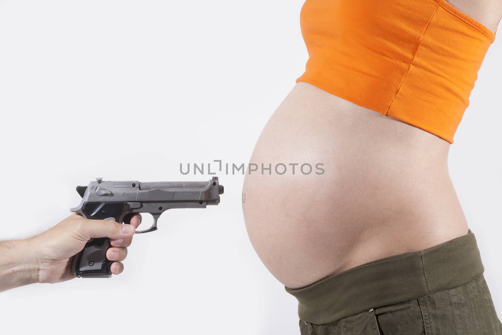 hand with pistol pointing tummy of naked pregnant woman