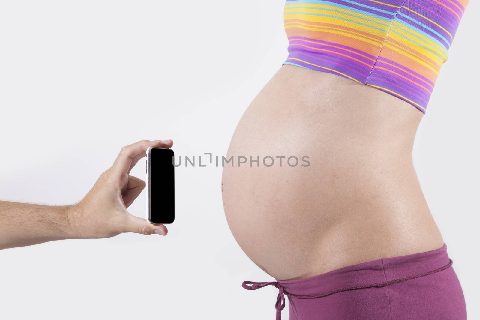 offering smartphone to tummy of naked pregnant woman