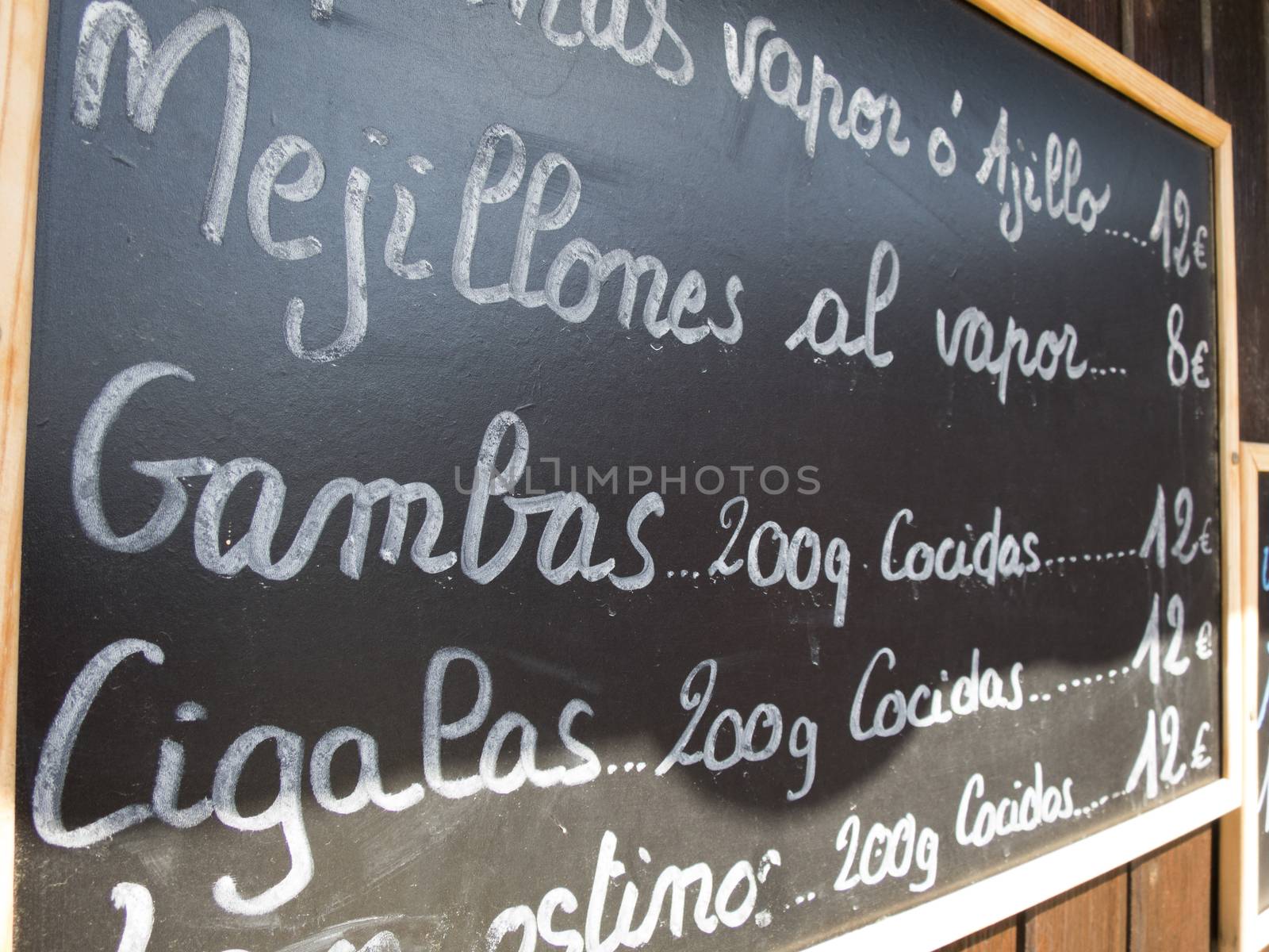 black placards spanish handwritten in brown wood wall with typical menu food dishes in Spain restaurant