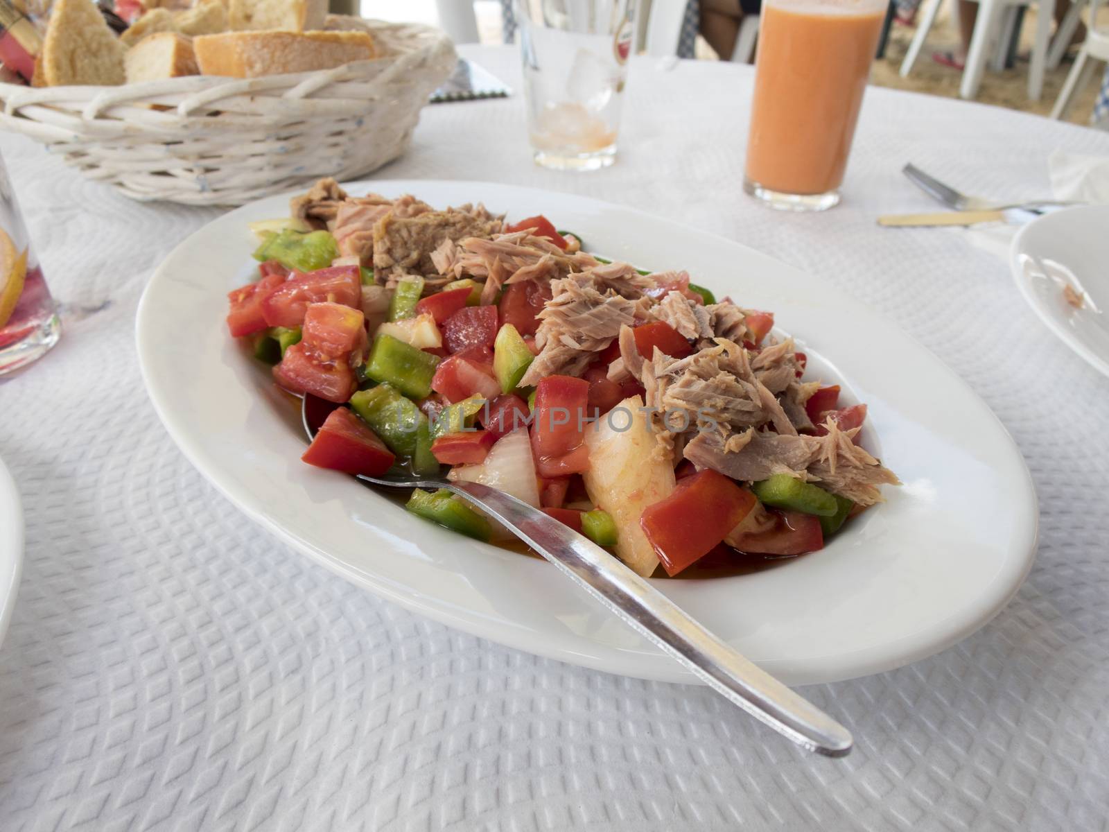 white tray with tomato green pepper tuna and onion salad on restaurant paper tablecloth