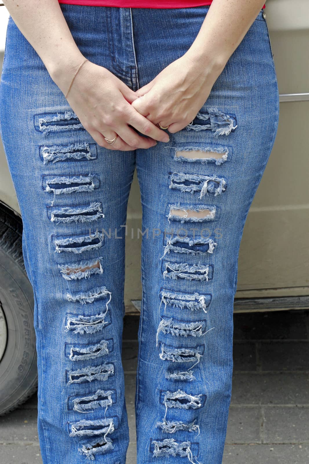 Woman in blue grunge jeans standing near auto