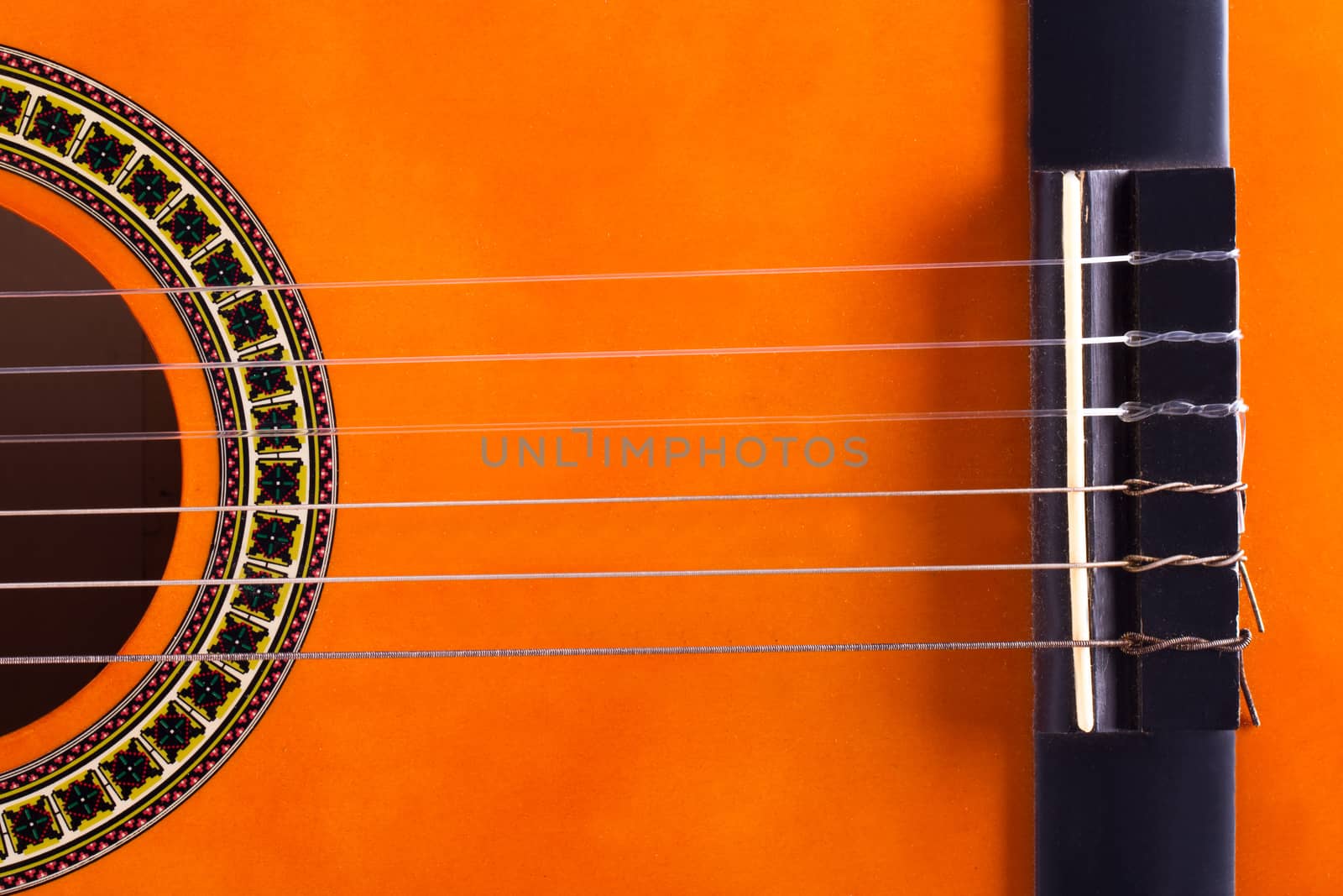 Detail view of orange wooden classical acoustic guitar.