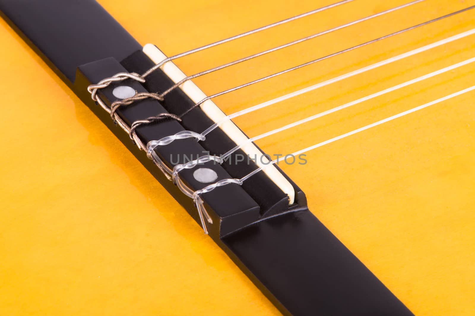 Detail view of yellow wooden classical acoustic guitar.