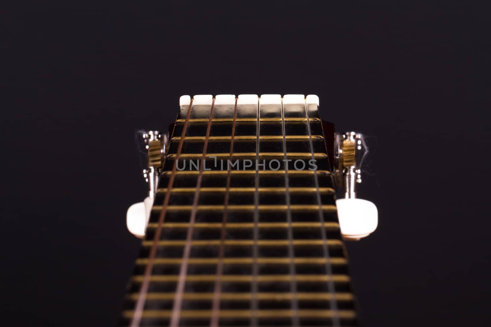 Detail view of classical guitar over black background.