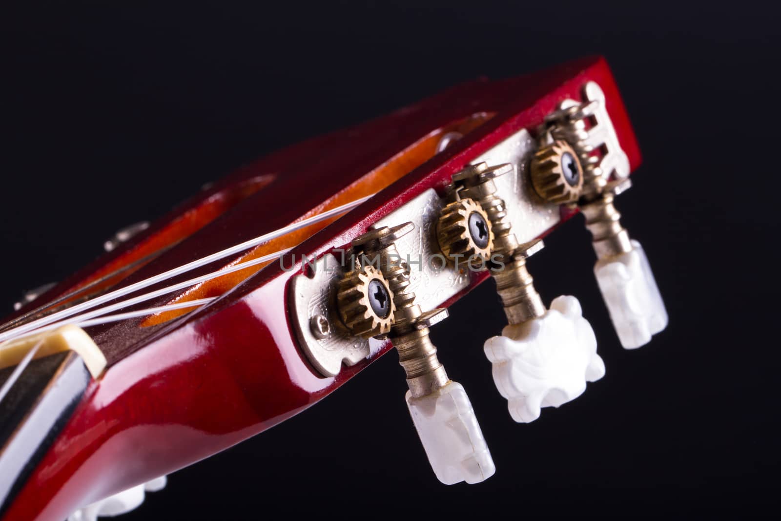 Detail view of fingerboard on classical acoustic guitar, over black background.