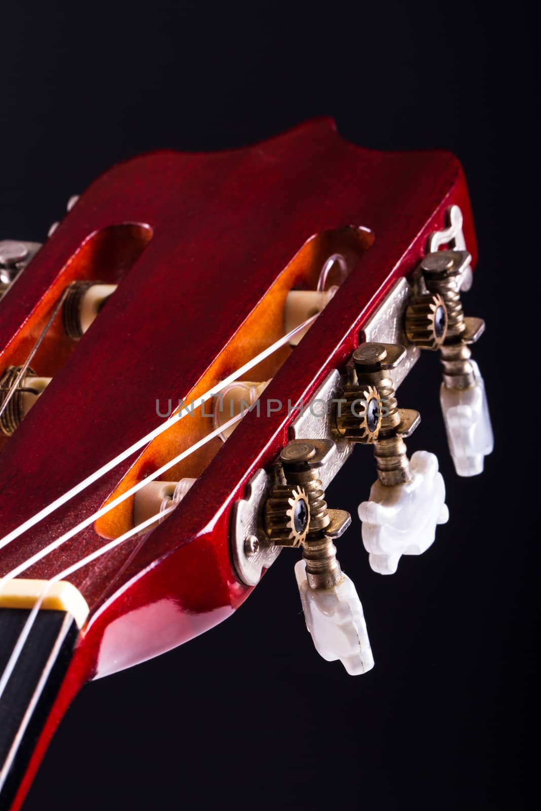 Detail view of fingerboard on classical acoustic guitar, over black background.