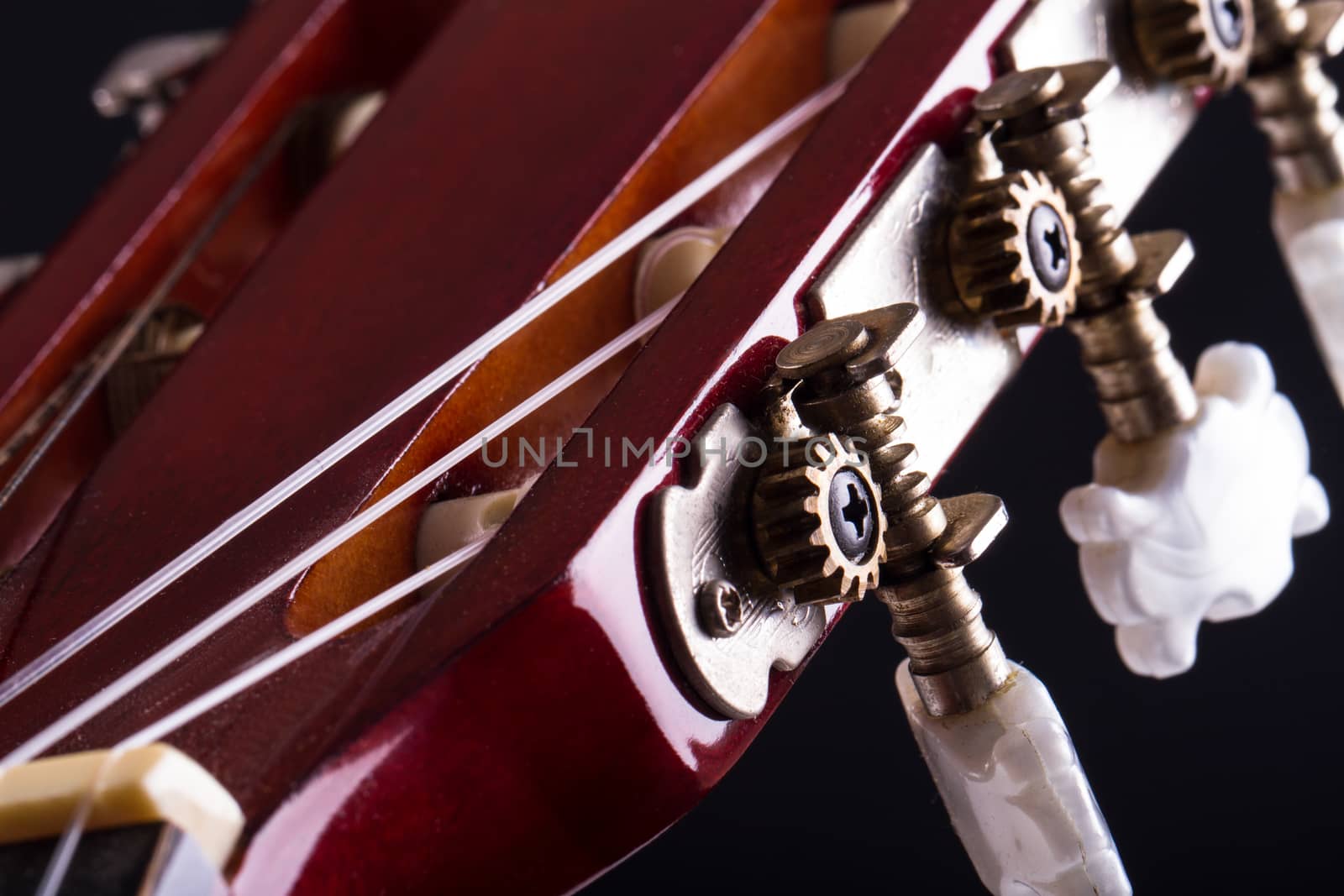 Close up view of fingerboard on classic guitar over black background.