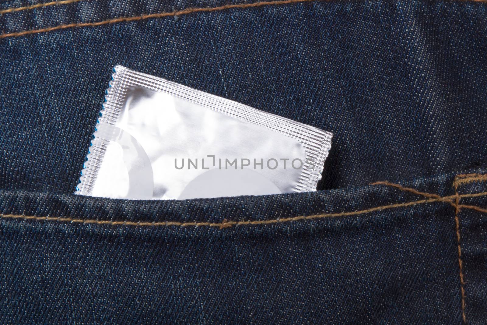 Condom packet in jeans pocket for safe sex.