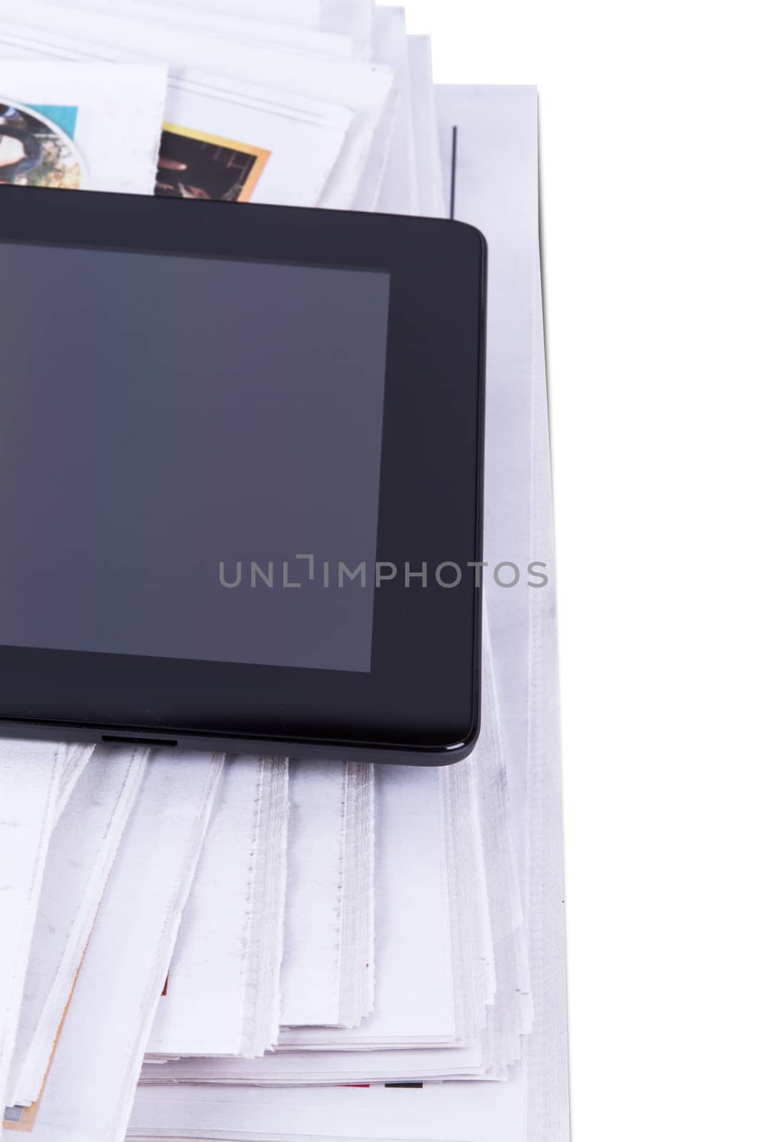 Stack of newspapers and tablet with blank screen, isolated on white background.