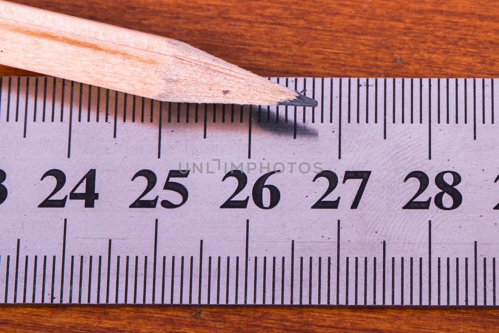 Close up view of wood pencil and steel ruler for engineering drawing on wooden table.