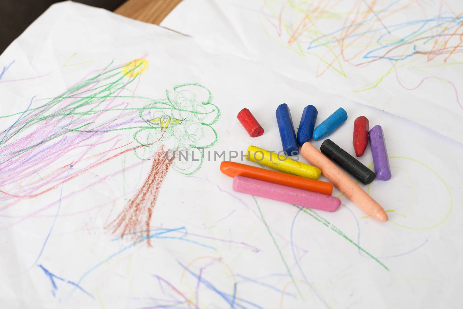 red blue orange pink purple black crayons on baby painting white sheet paper on table inside home