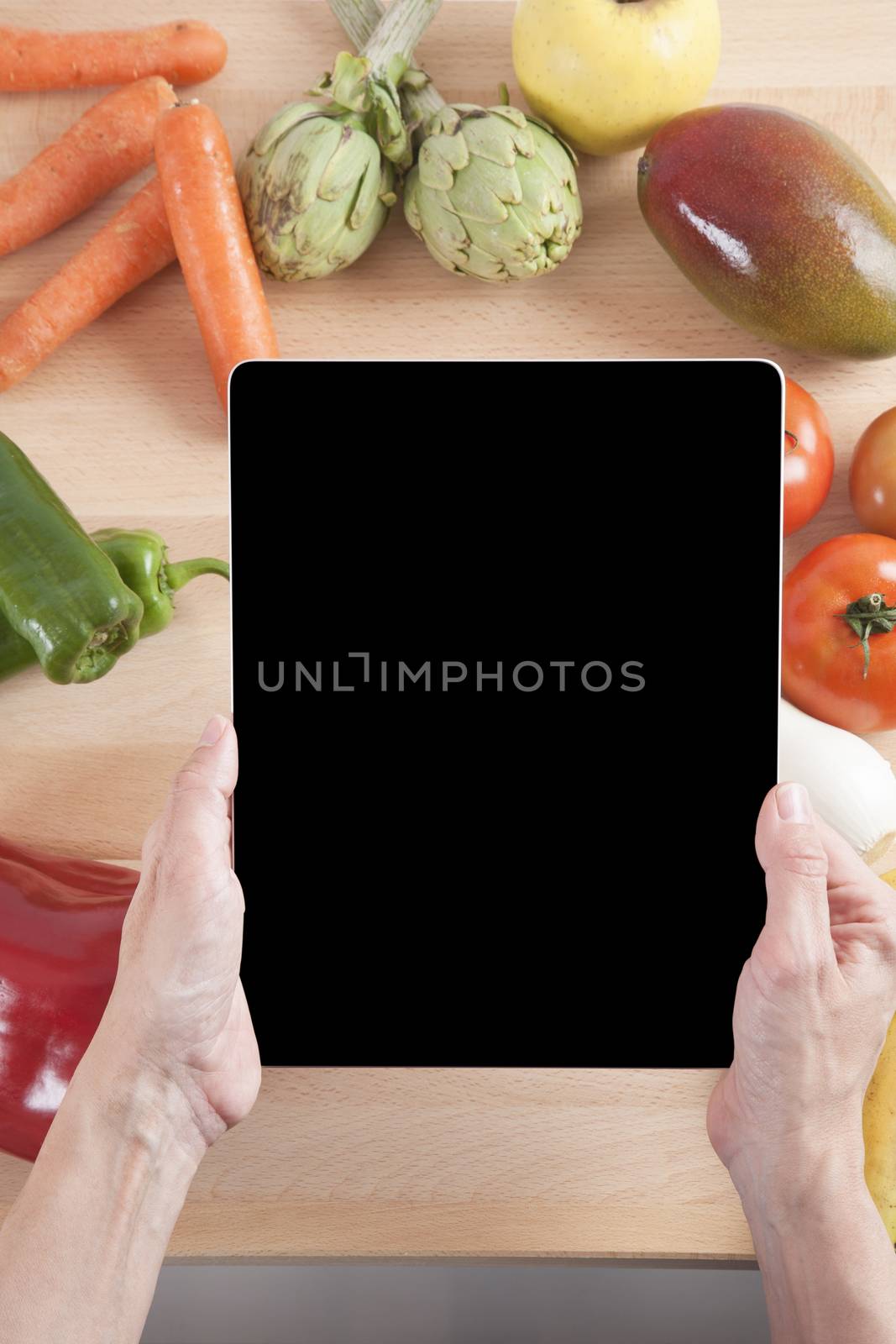 woman hands with blank screen tablet still life fruits and vegetables around on brown wood plank