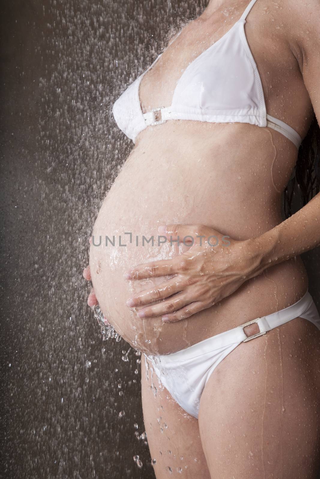 pregnant woman with white bikini under shower water