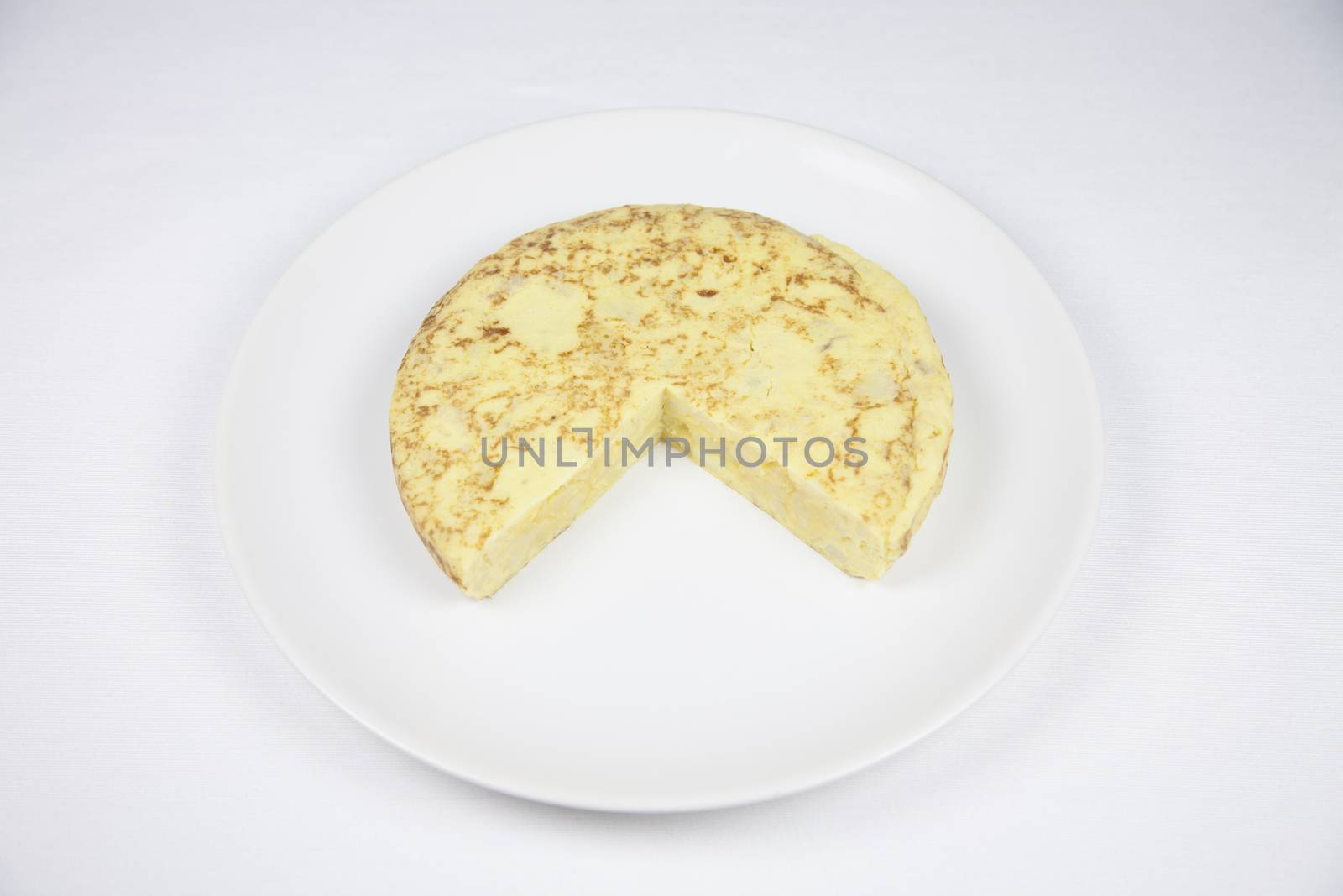 white dish with yellow spanish potato omelette on grey tablecloth