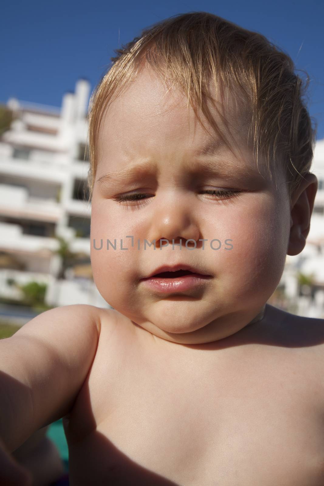 one year blonde baby naked crying outdoors on summer time