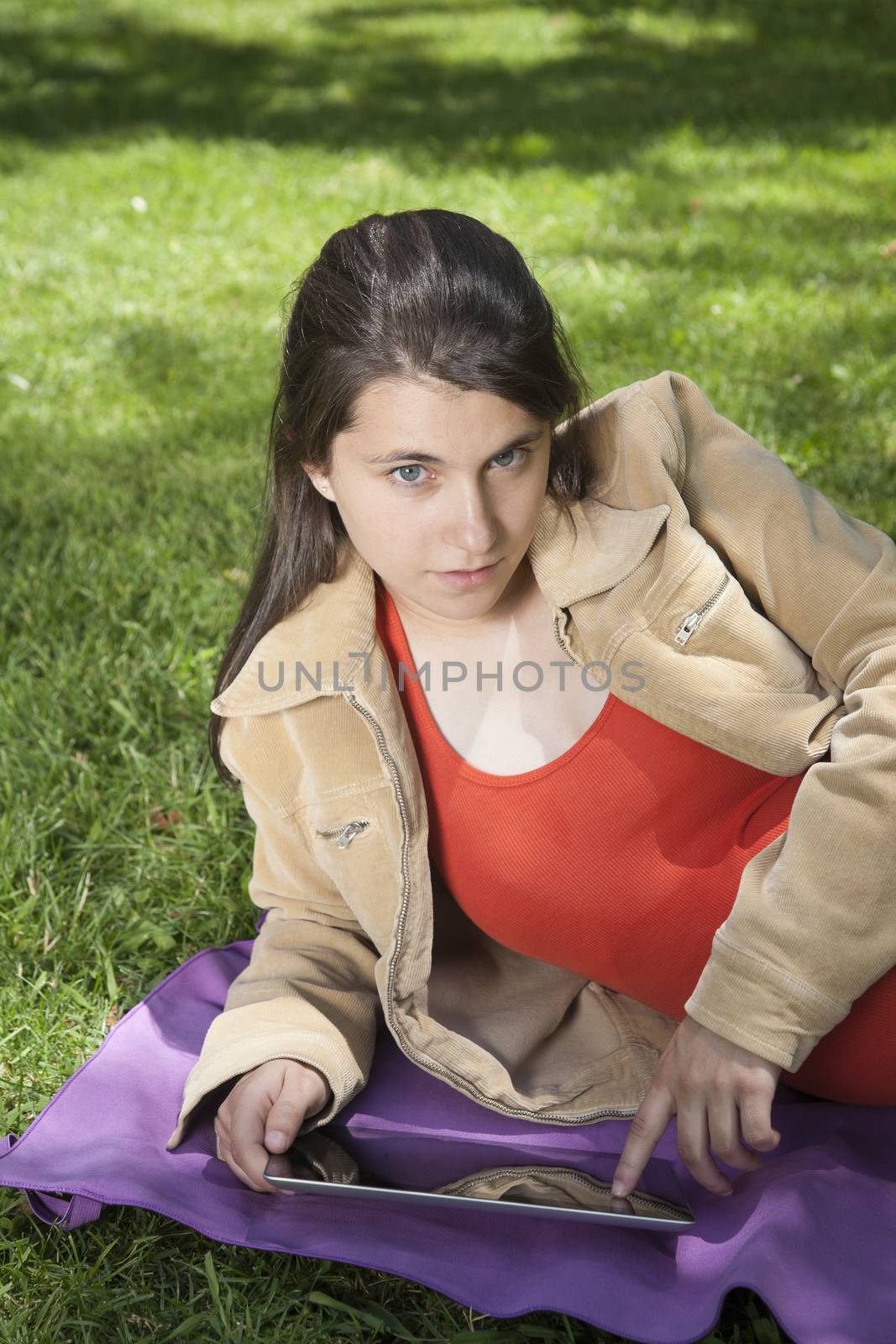 pregnant young woman with orange shirt touching tablet at a park in Madrid Spain Europe