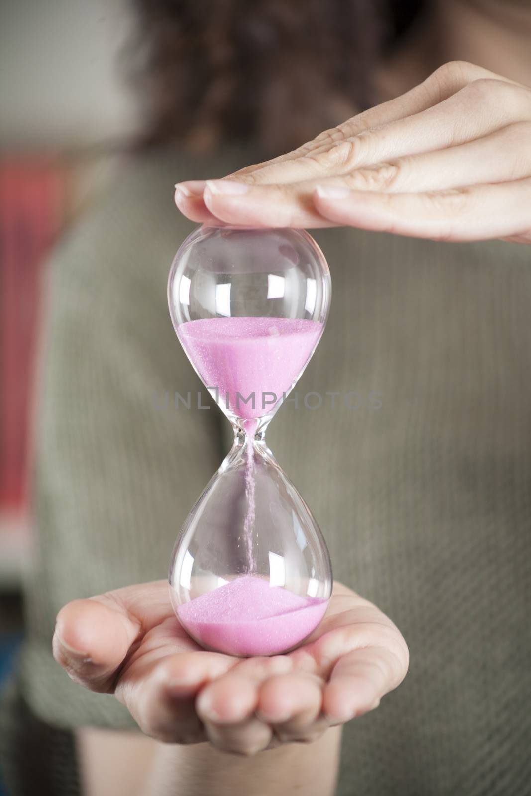 pink sand clock in woman hands by quintanilla