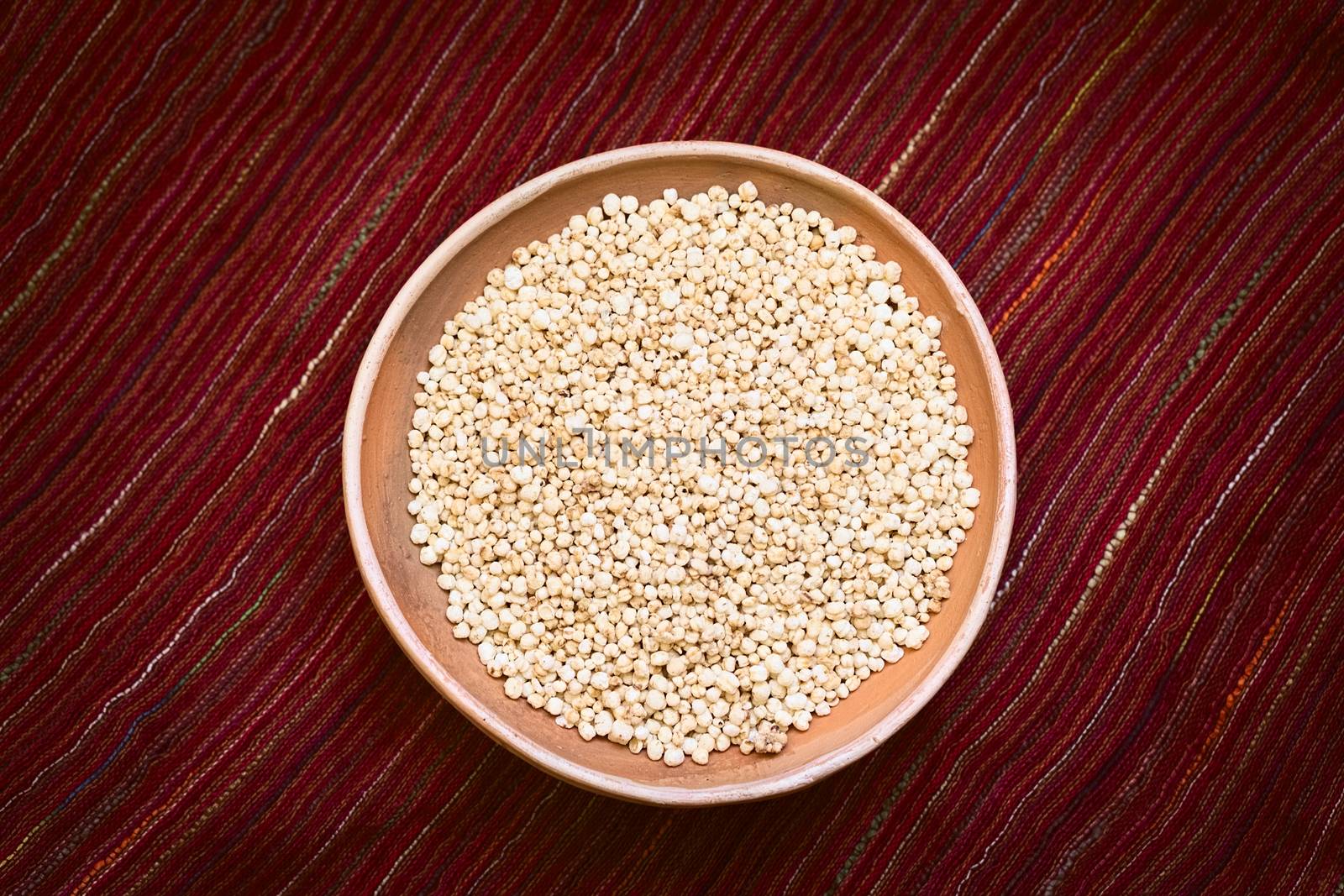 Overhead shot of popped white quinoa (lat. Chenopodium quinoa) cereal in bowl on red textile photographed with natural light 